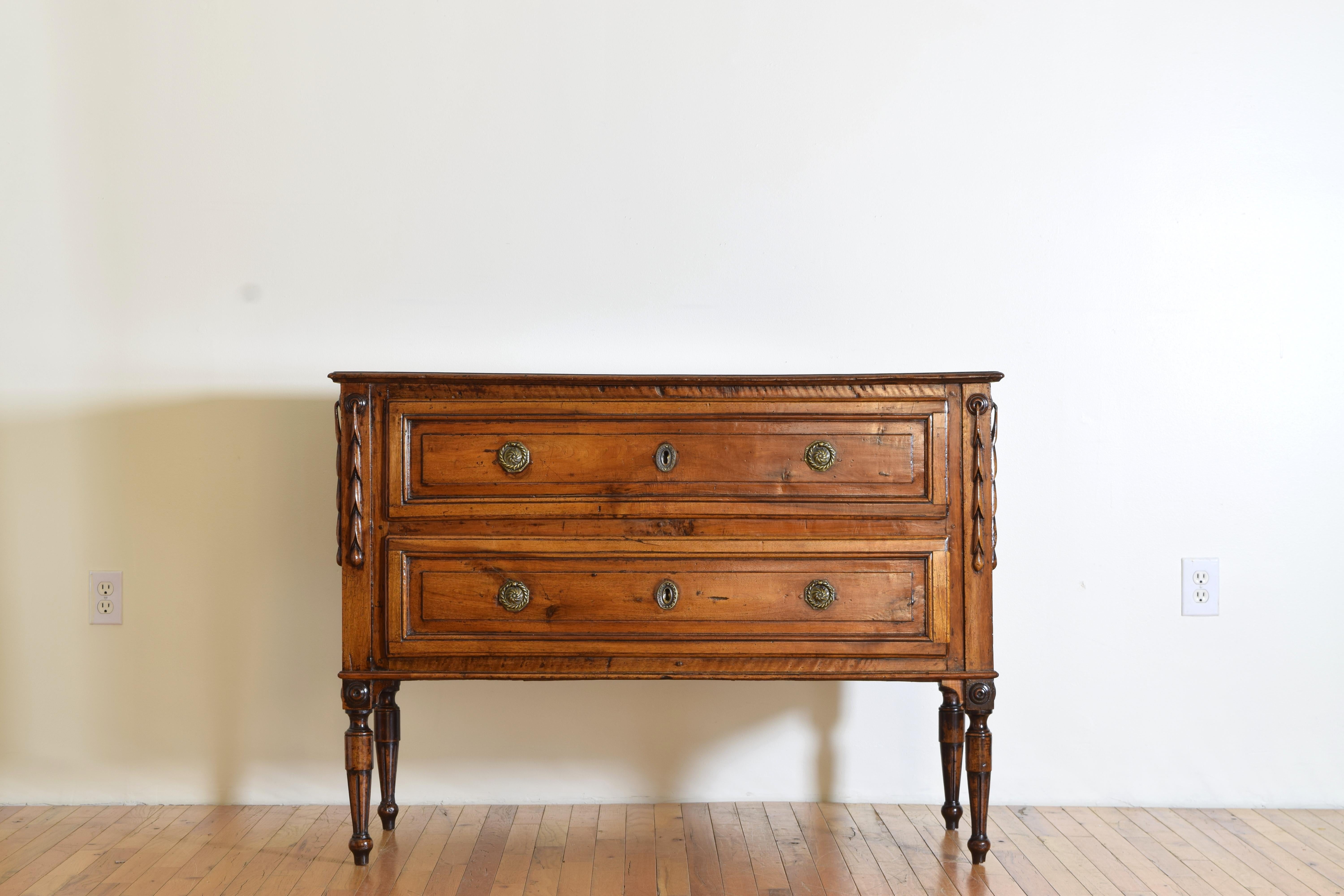 Having a rectangular top with molded edge atop a conforming case housing two paneled drawers with octagonal brass pulls, with uniquely carved hanging leaves at the upper corners, the turned, fluted, and tapering legs with turned medallions above