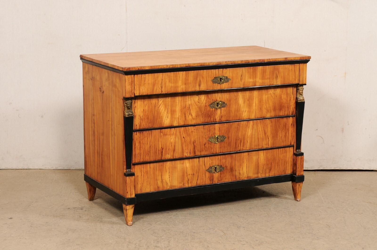 An Italian Neoclassical chest, with black accents and and unusual feet, from the early 19th century. This antique chest of drawers from Italy features a rectangular-shaped top above a case which houses four drawers flanked within Roman column-style