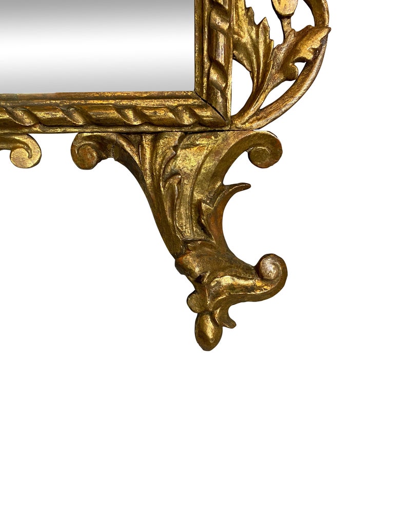 With urn and leaf finial over scrolls and leaf carving over a not original but old mirror plate within a carved frame, ending on scroll feet.