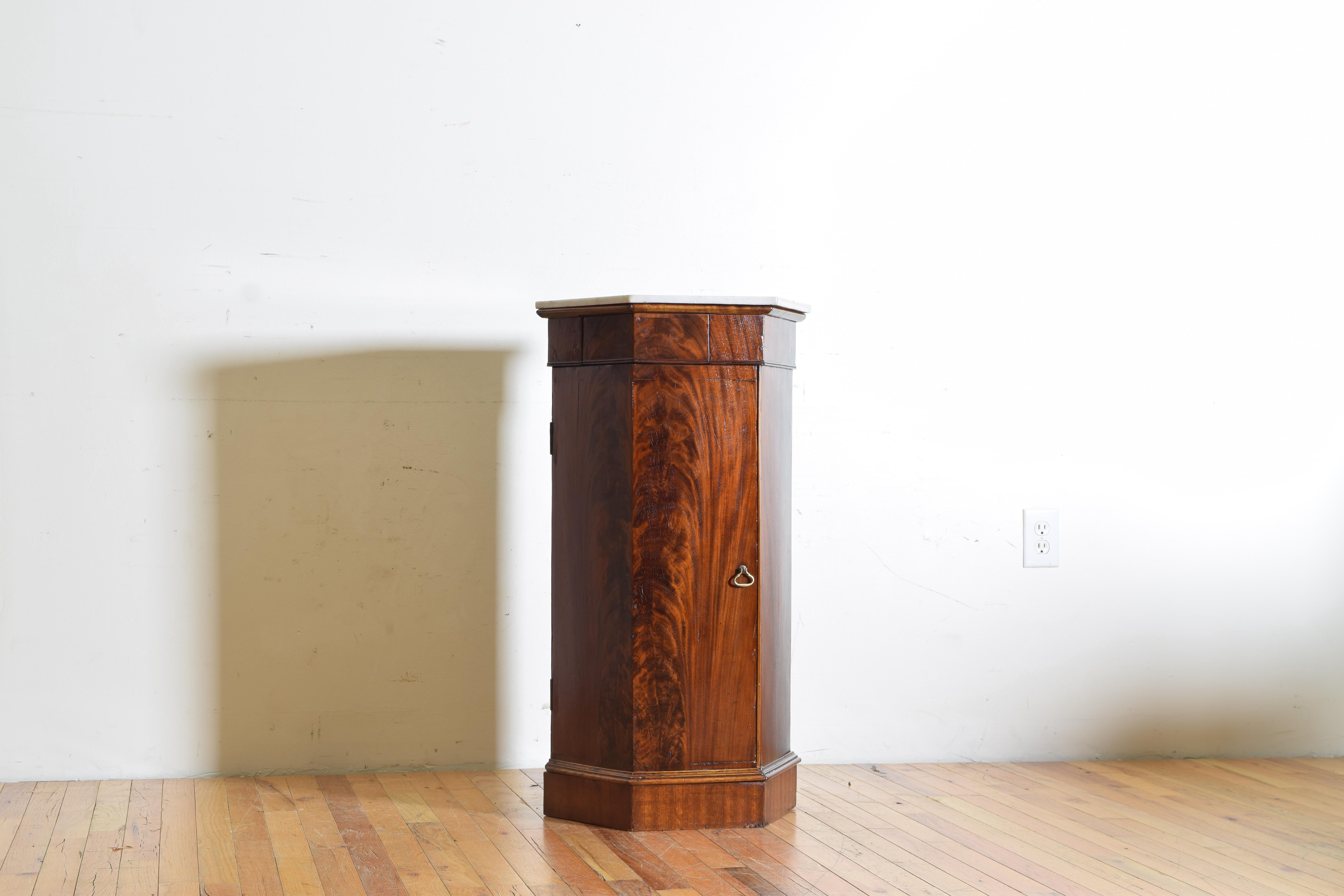 Having a hexagonal marble top atop a mahogany cabinet housing one drawer above a vertical door opening to reveal an interior with a shelf, raised on a shaped base with a molded edge.