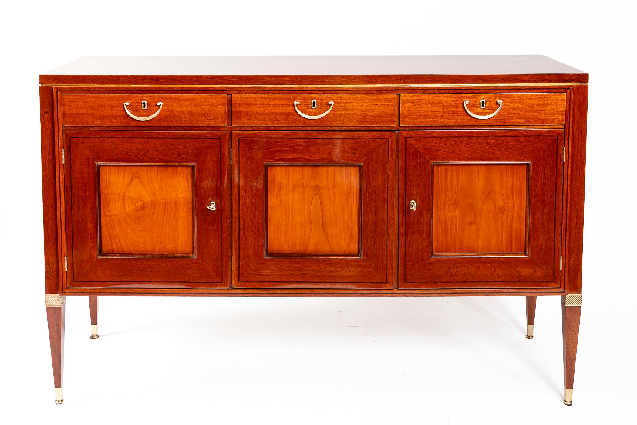 Buffet raffiné du milieu du siècle en bois fruitier massif bicolore composé de trois tiroirs sur trois tiroirs reposant sur quatre pieds fuselés et droits et orné d'élégantes ferrures en laiton poli non laqué et de garnitures ébonisées. Son Label