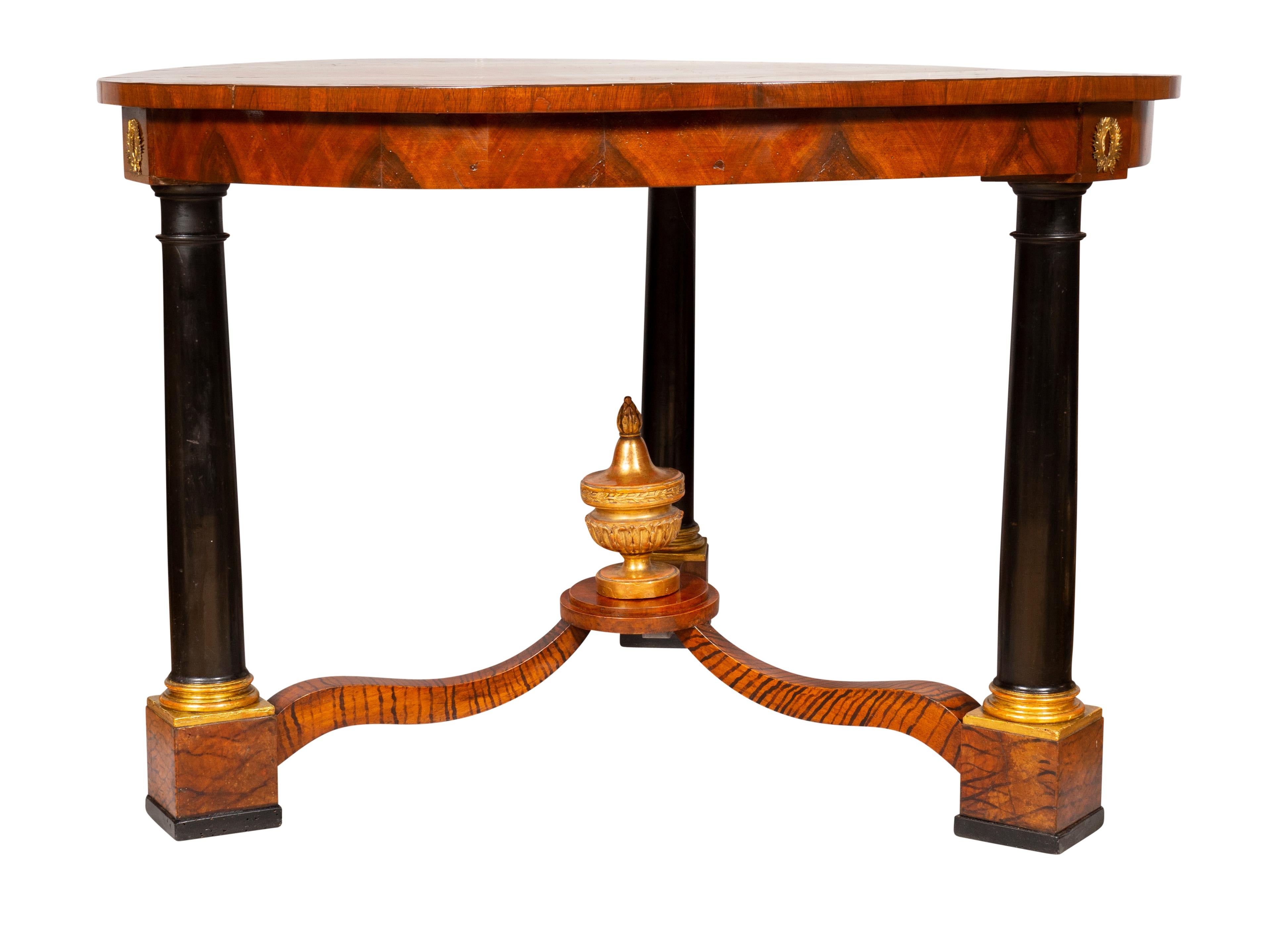 Circular top with starburst inlays over a conforming frieze with gilt metal wreaths at top of legs raised on three ebonized columns with faux painted stretcher and gilt wood central finial.