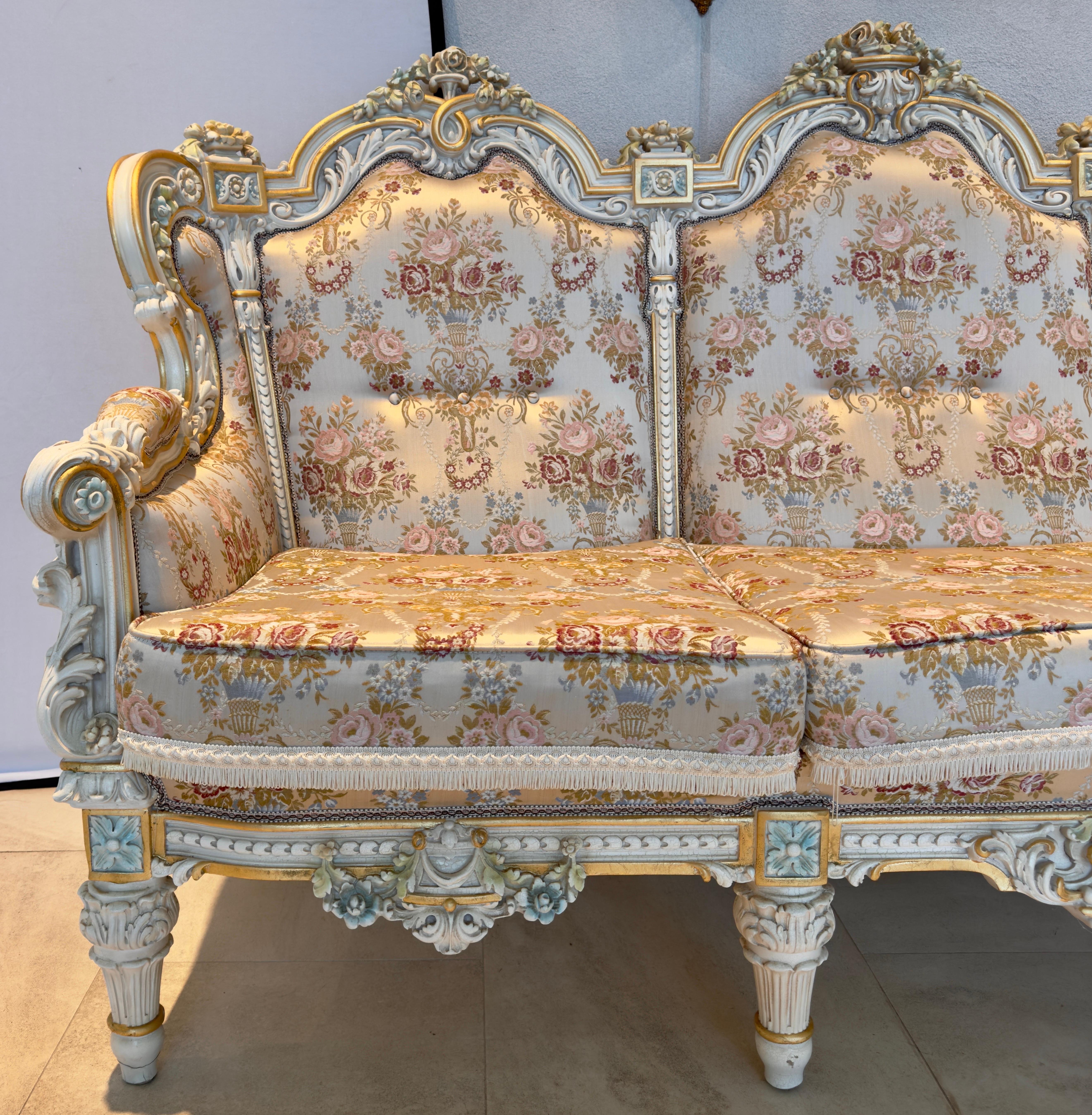 A stunning Italian neoclassical baroque Three-Seater Sofa, a symphony of opulence and comfort designed to adorn your space with unrivaled elegance. 
Carved from the finest materials, the sofa exudes sophistication in its off-white antique finish,