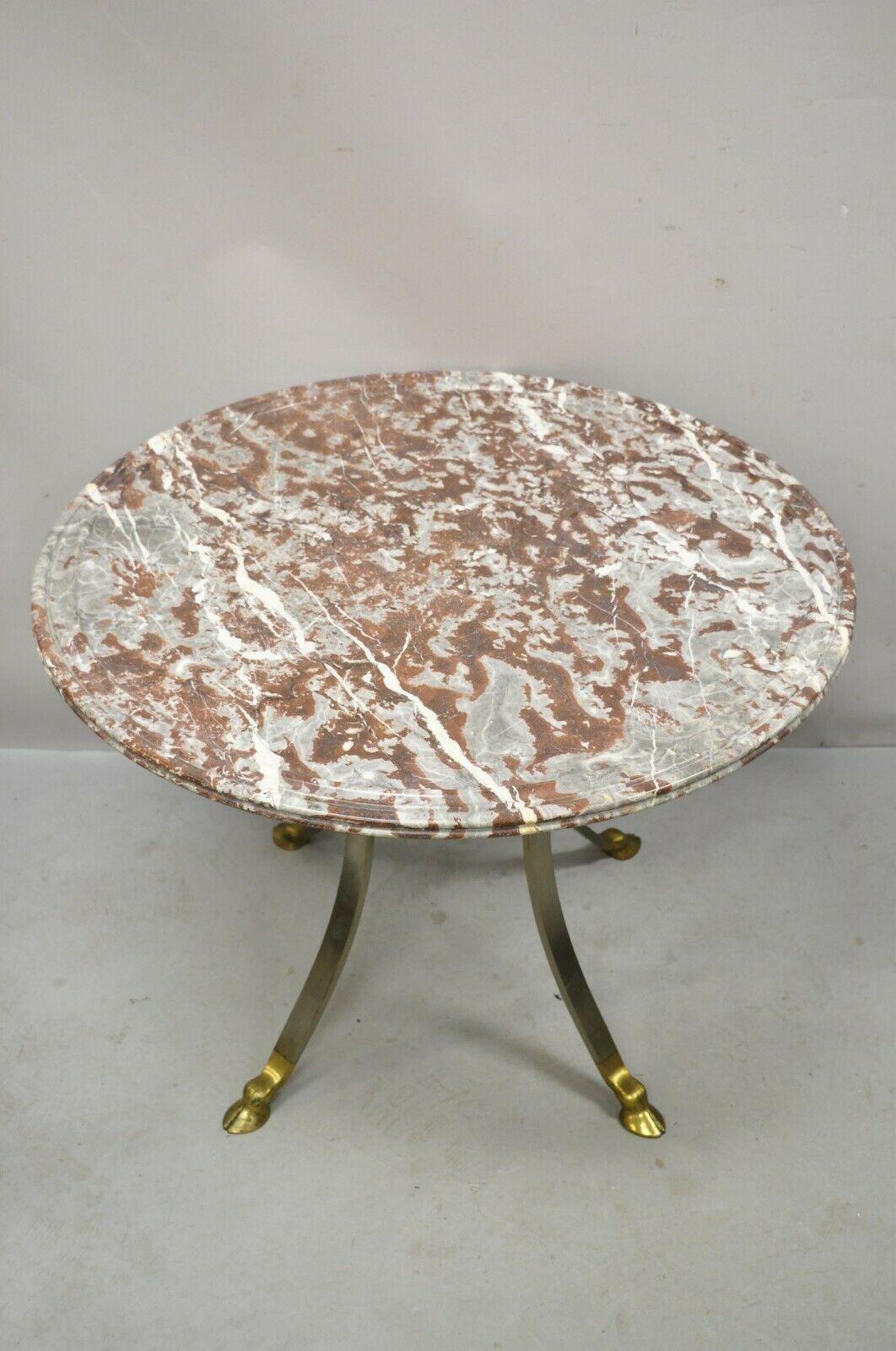 Table de centre de style néoclassique italien en laiton avec pied en forme de sabot et plateau en marbre rouge de 32 pouces. L'article présente un plateau rond en marbre rose à bord sculpté, une base en laiton et acier, des pieds sabots en laiton,