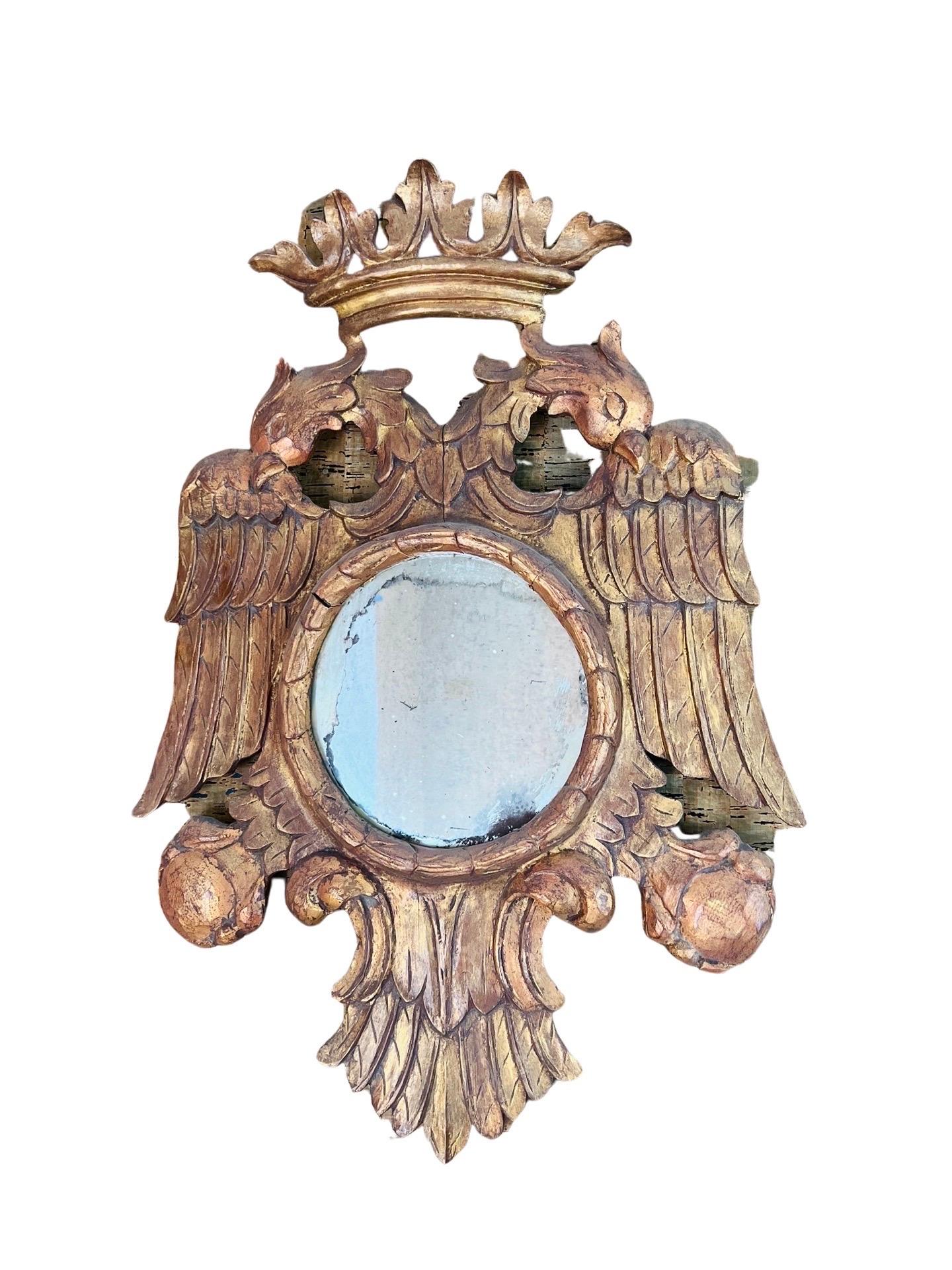 Italian made magnificent carved giltwood mirror frame in the form of a crowned bicephal eagle. Highly decorative frames with double-headed eagles surmounted by a crown, symmetric wings and tails holding the central circular mirror and the bird claws