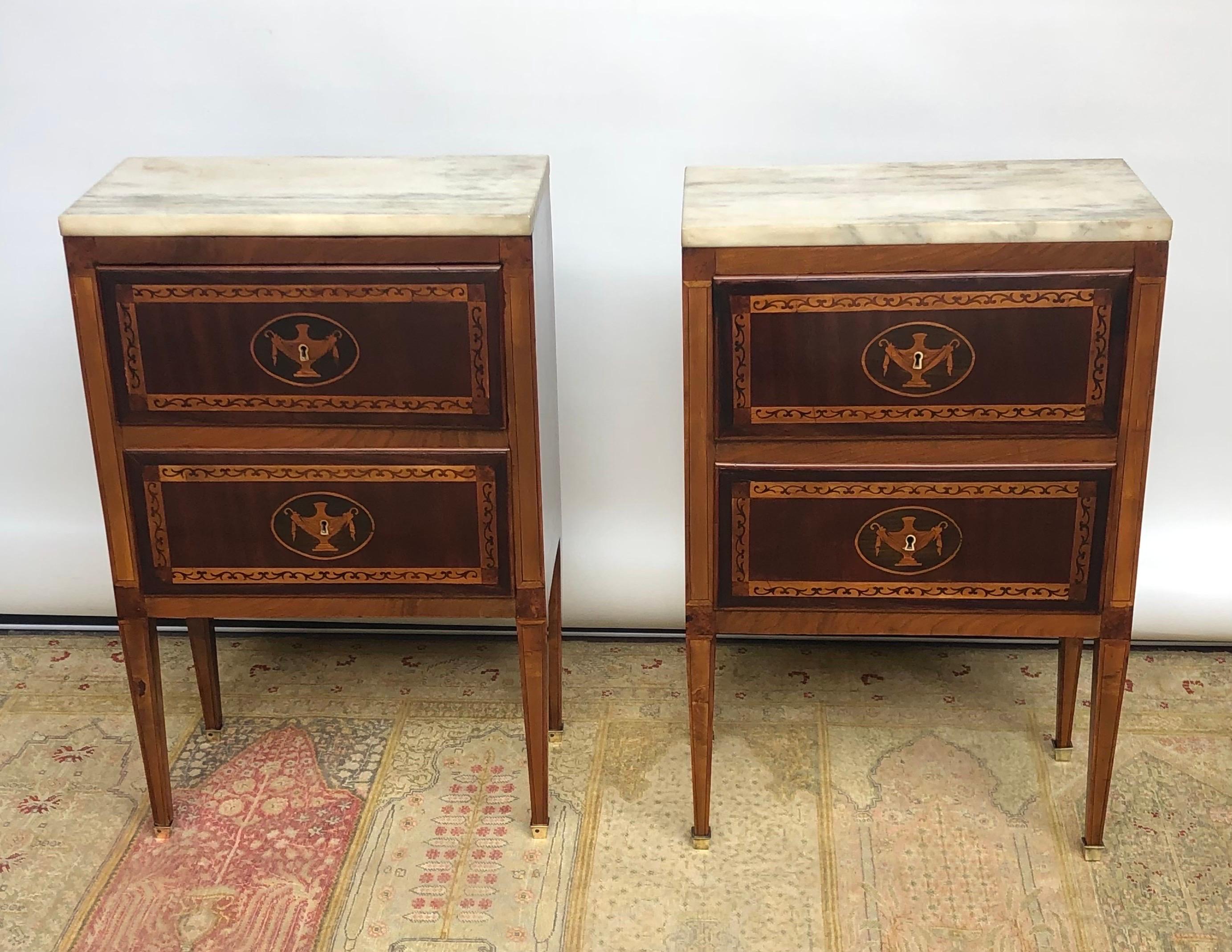 This Elegant Pair of Neoclassical Marquetry Commodes with Marble Tops where made in Italy in the late Eighteenth Century.  The Italian Commodes have walnut, mahogany and marquetry inlayed drawers above square tapered legs with brass cups on the