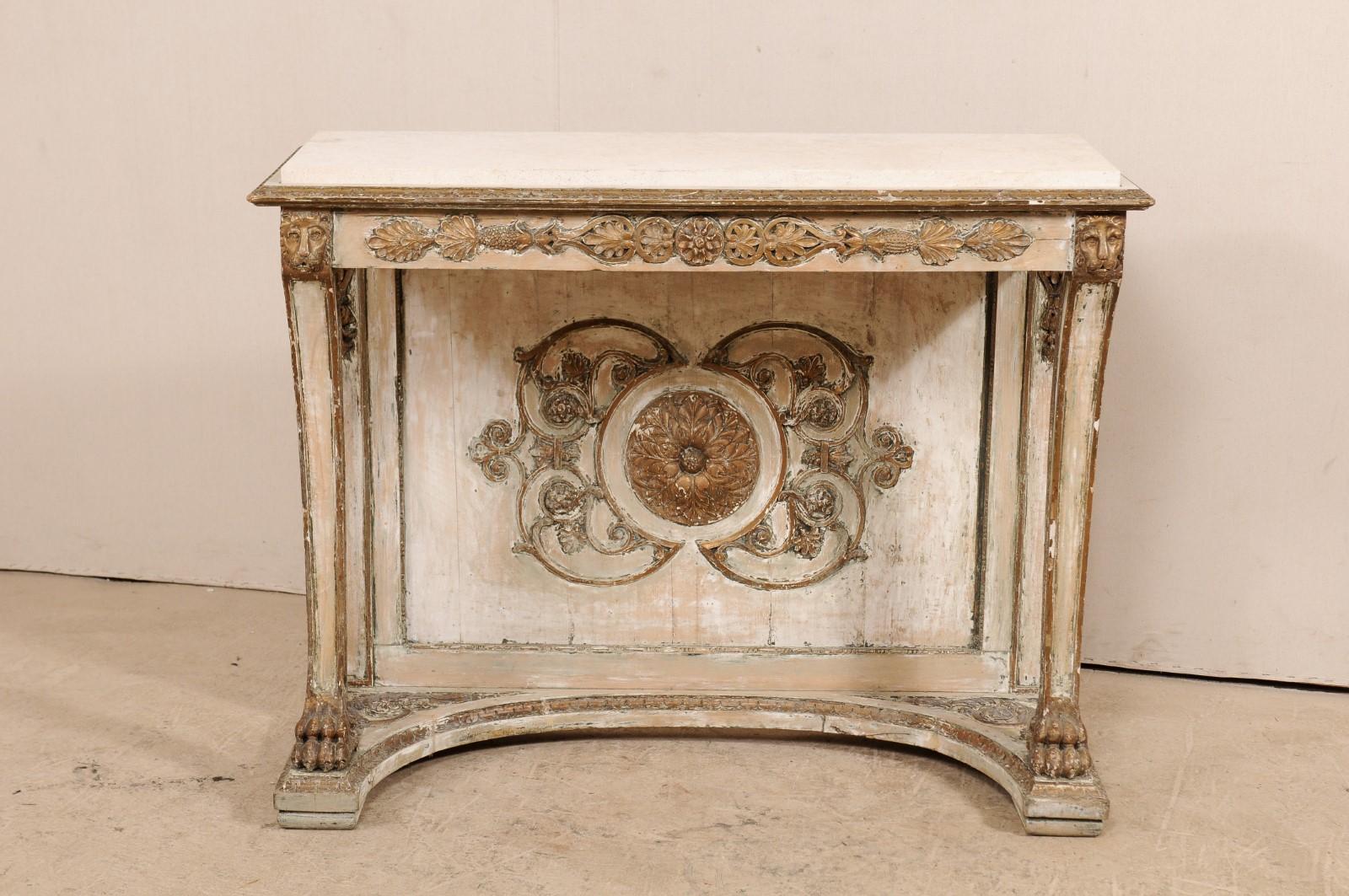 An Italian neoclassical parcel-gilt and white painted console table, circa 1830. This Fine antique neoclassical style table from Italy features a rectangular-shaped honed stone top, which rests within a carved lip, atop a skirt with richly carved