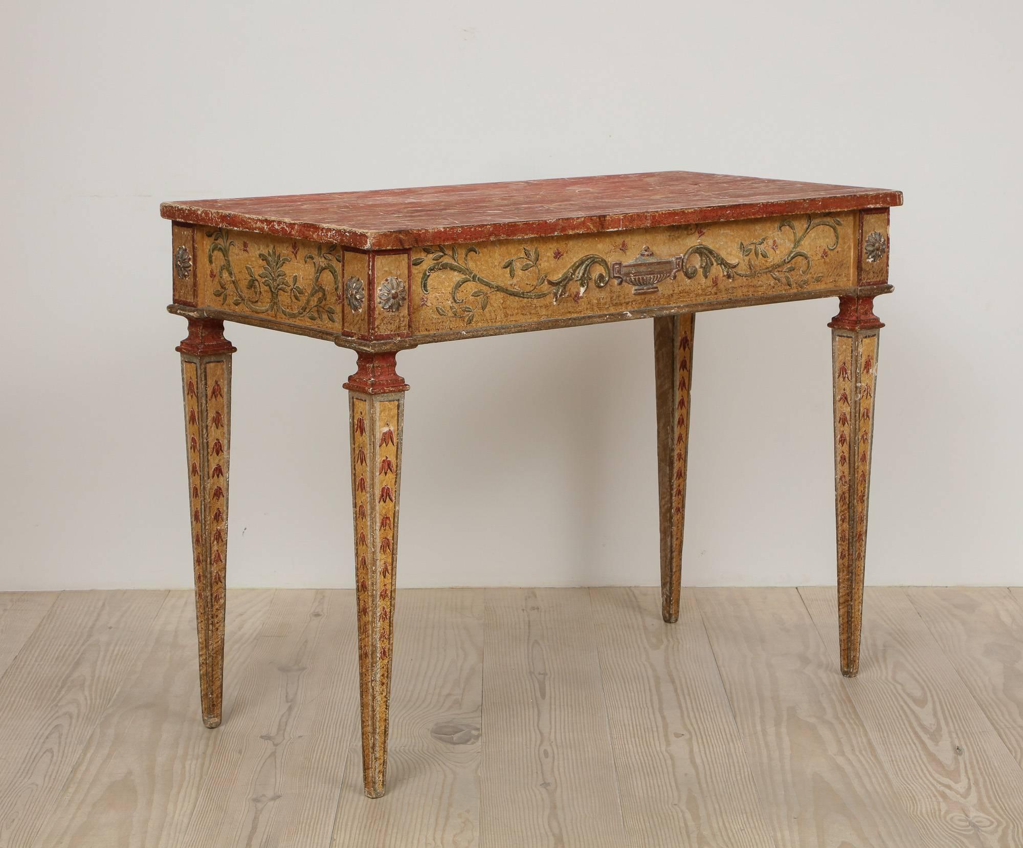 A pair of Italian neoclassical consoles, 19th century with faux marble tops and exceptional painting.  Origin: Venice, Italy. 
Each apron with raised gessoed and painted details of and urn and flowing leaves; the legs with rosettes all with original