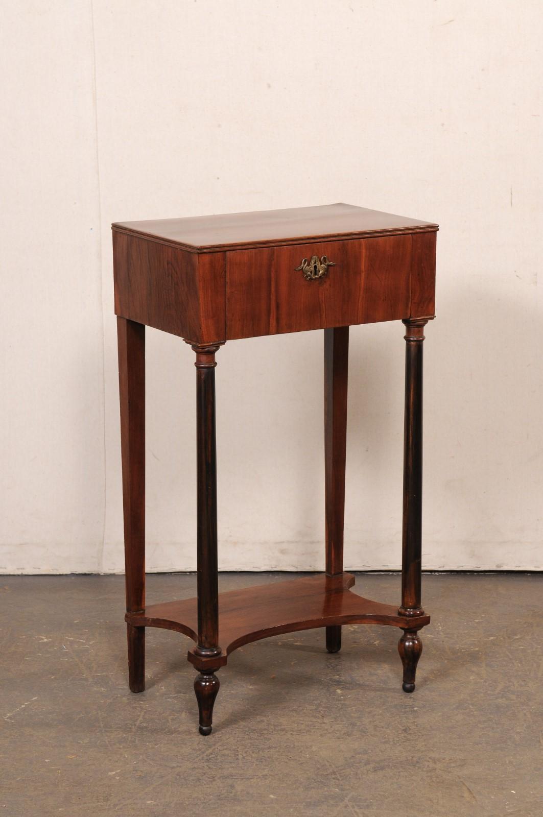 An Italian Neoclassical style end table, with drawer and lower secondary shelf, from the 19th century. This antique table from Italy, circa 1820's, has a rectangular-shaped top, over apron which houses a single drawer (fitted with elegant