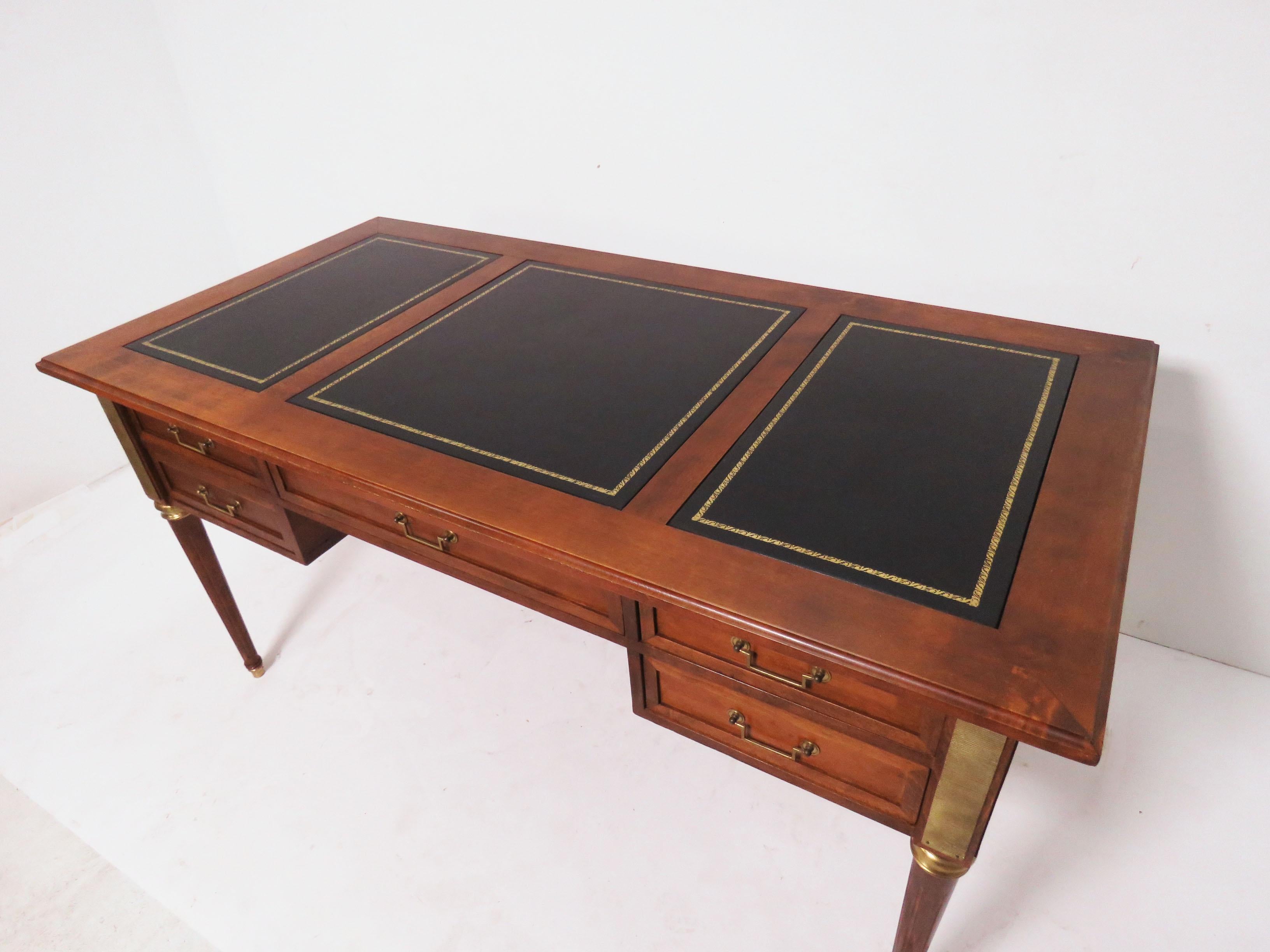 Executive writing desk in a modern adaptation of the neoclassical style, in walnut with combed brass ormolu adornments and embossed leather paneled surfaces, made in Italy, circa 1960s.