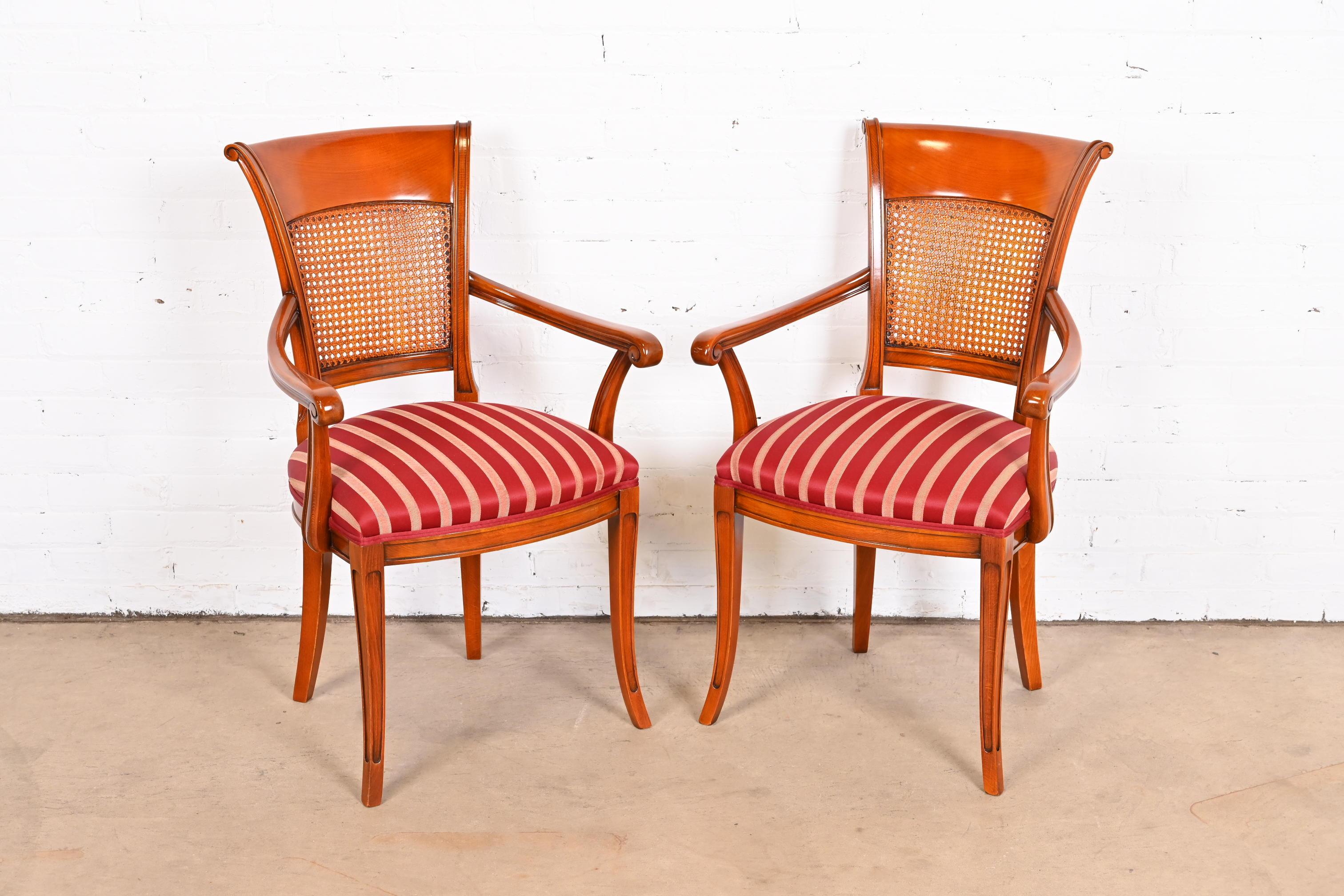 A gorgeous pair of Neoclassical style club chairs or dining armchairs

Italy, 20th Century

Solid carved fruitwood frames, with caned backs and striped satin upholstered seats.

Measures: 22.5
