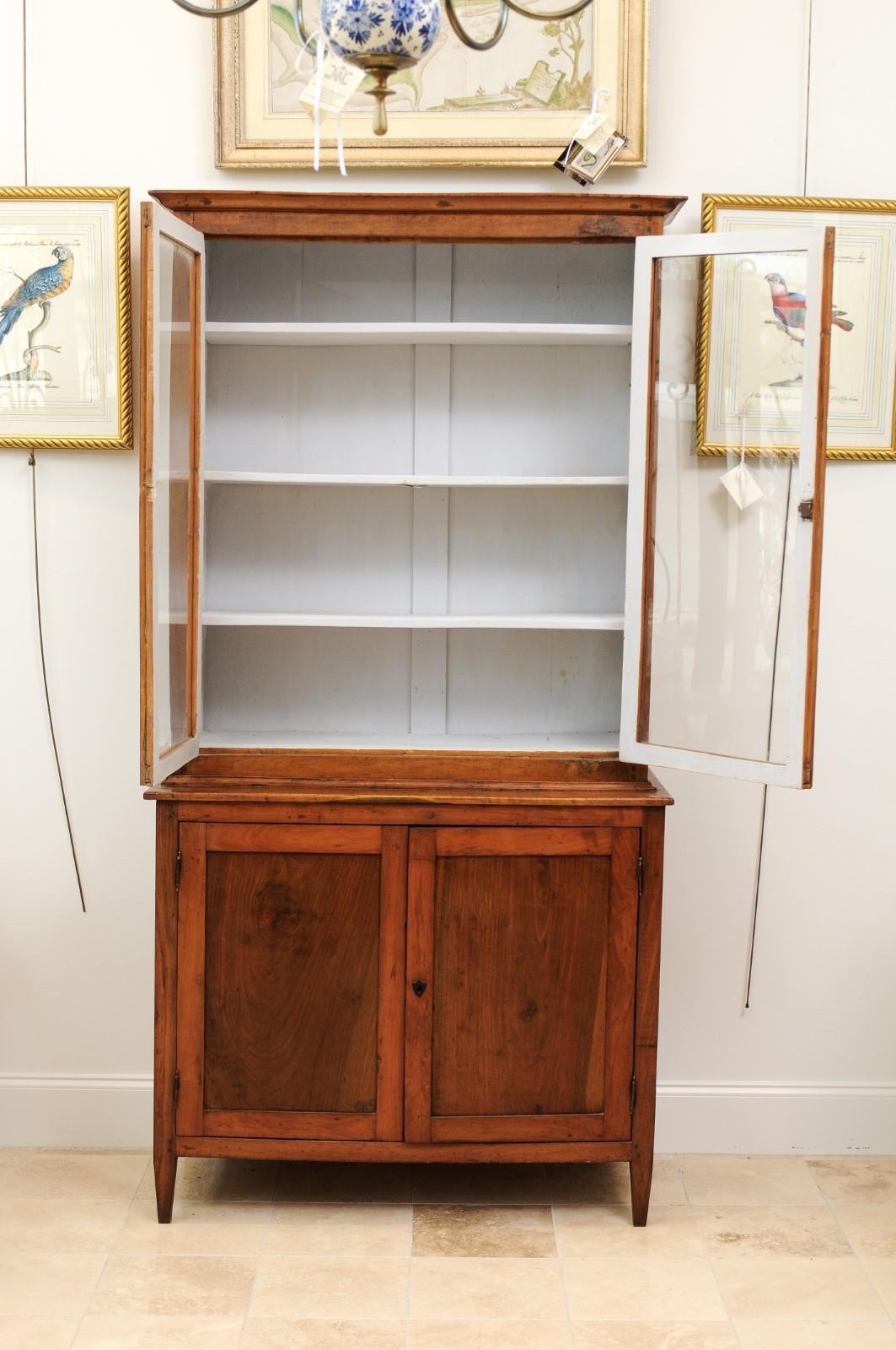 A late 18th century Italian neoclassical fruitwood bookcase featuring glass paneled doors over 2 cabinet doors on tapered feet.

   