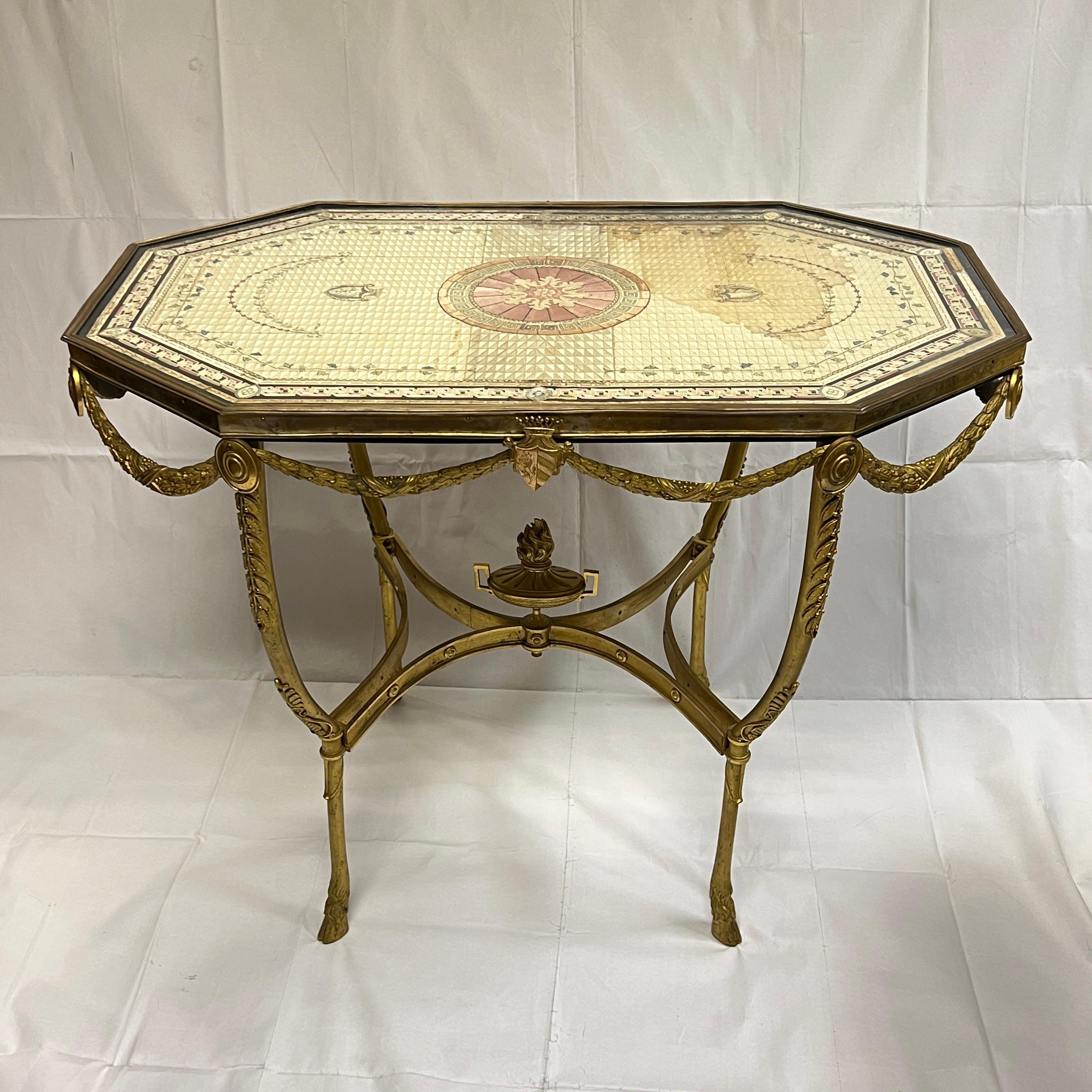 Extraordinaire table centrale italienne du XIXe siècle en bronze doré avec plateau en soie peint à la main et recouvert d'un plateau en verre, avec armoiries familiales représentant des rayures dorées sur fond bleu avec lion rampant.  Sous-face