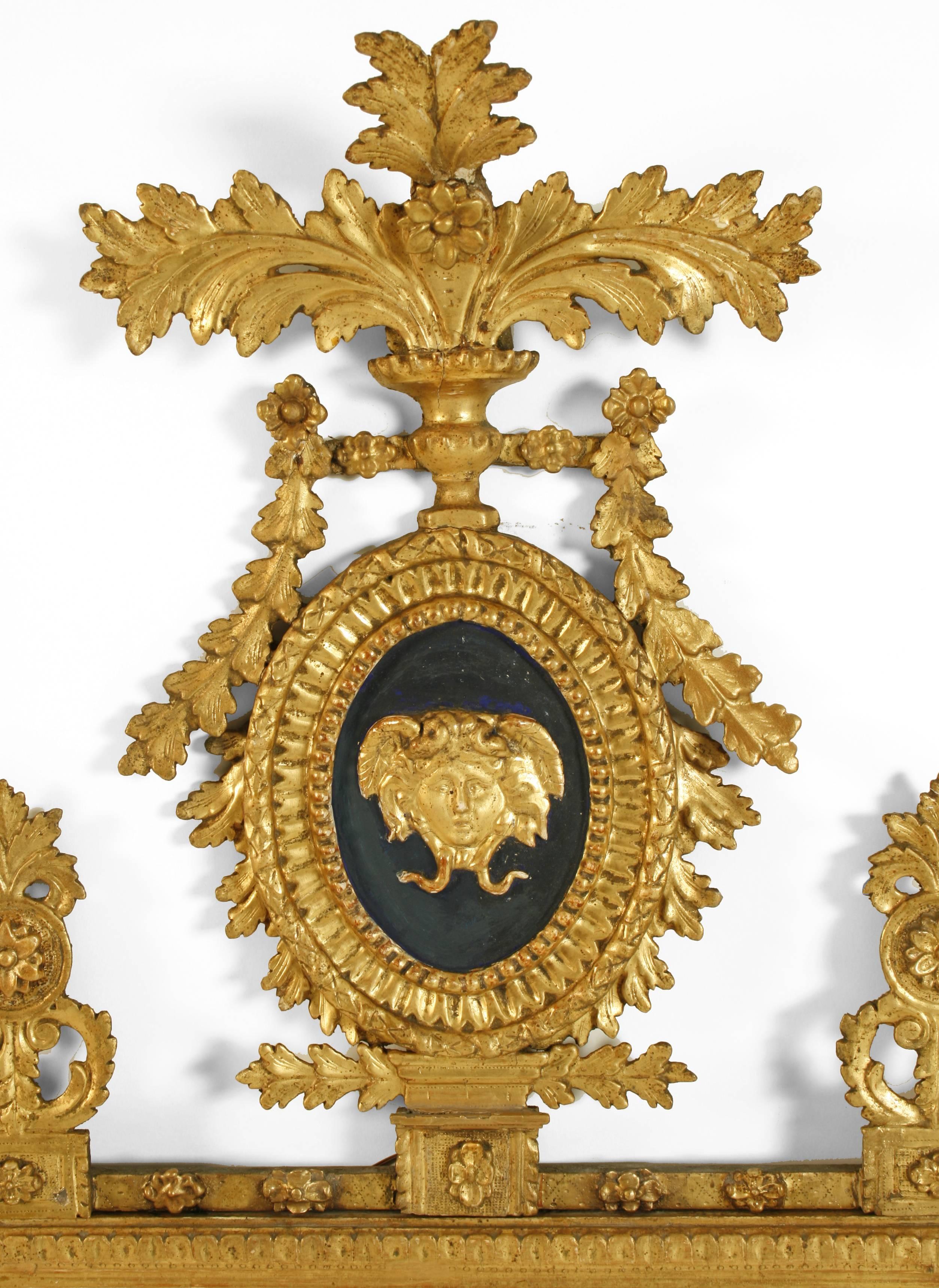 An Italian neoclassical giltwood mirror last quarter of the 18th century, the rectangular mirror plate surmounted by an oval portrait medallion of Medusa, set on a blue ground, and foliate swags, the corners marked with urns; the whole decorated