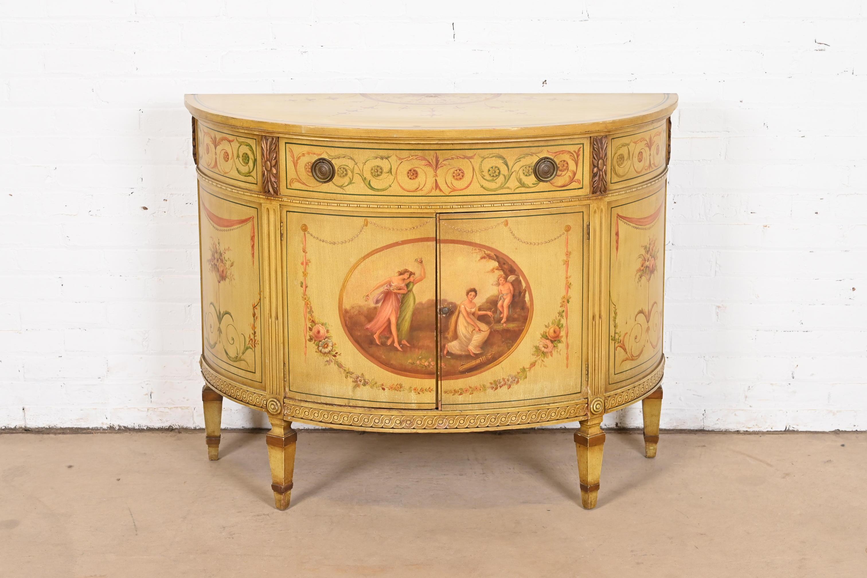 A gorgeous Neoclassical or Louis XVI style demilune console or bar cabinet

Italy, Circa 1940s

Hand painted case and top, featuring allegorical scenes, with original brass hardware.

Measures: 44.5