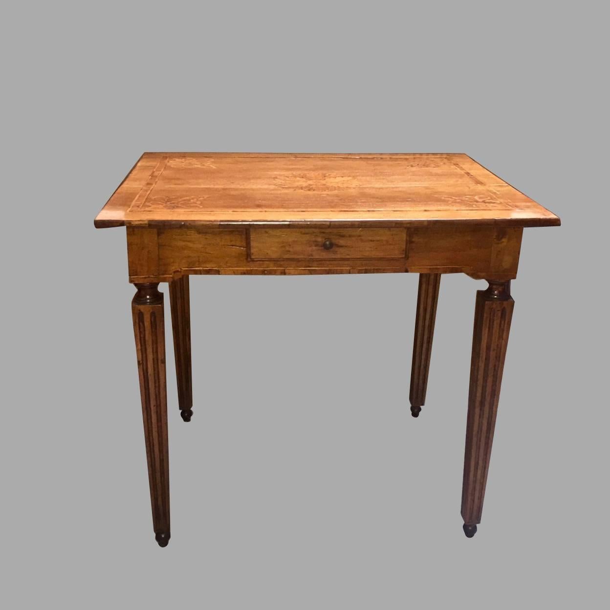 A very pretty Italian neoclassical period walnut center table, the marquetry inlaid top with an elaborate central floral medallion and complementary inlaid corners above a line inlaid apron with a single drawer, supported on fluted square tapered