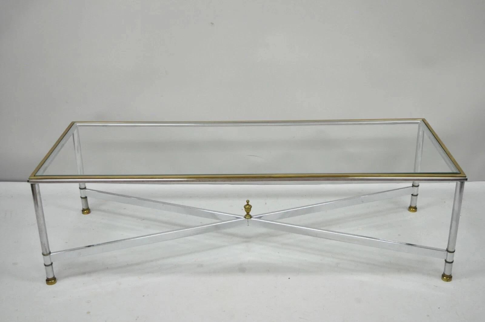 Vintage Italian Neoclassical Maison Jansen Style Steel & Brass Rectangular Coffee Table. L'article se caractérise par un cadre en acier chromé, des accents et des garnitures en laiton, un piètement à roulettes, un plateau en verre encastré et une
