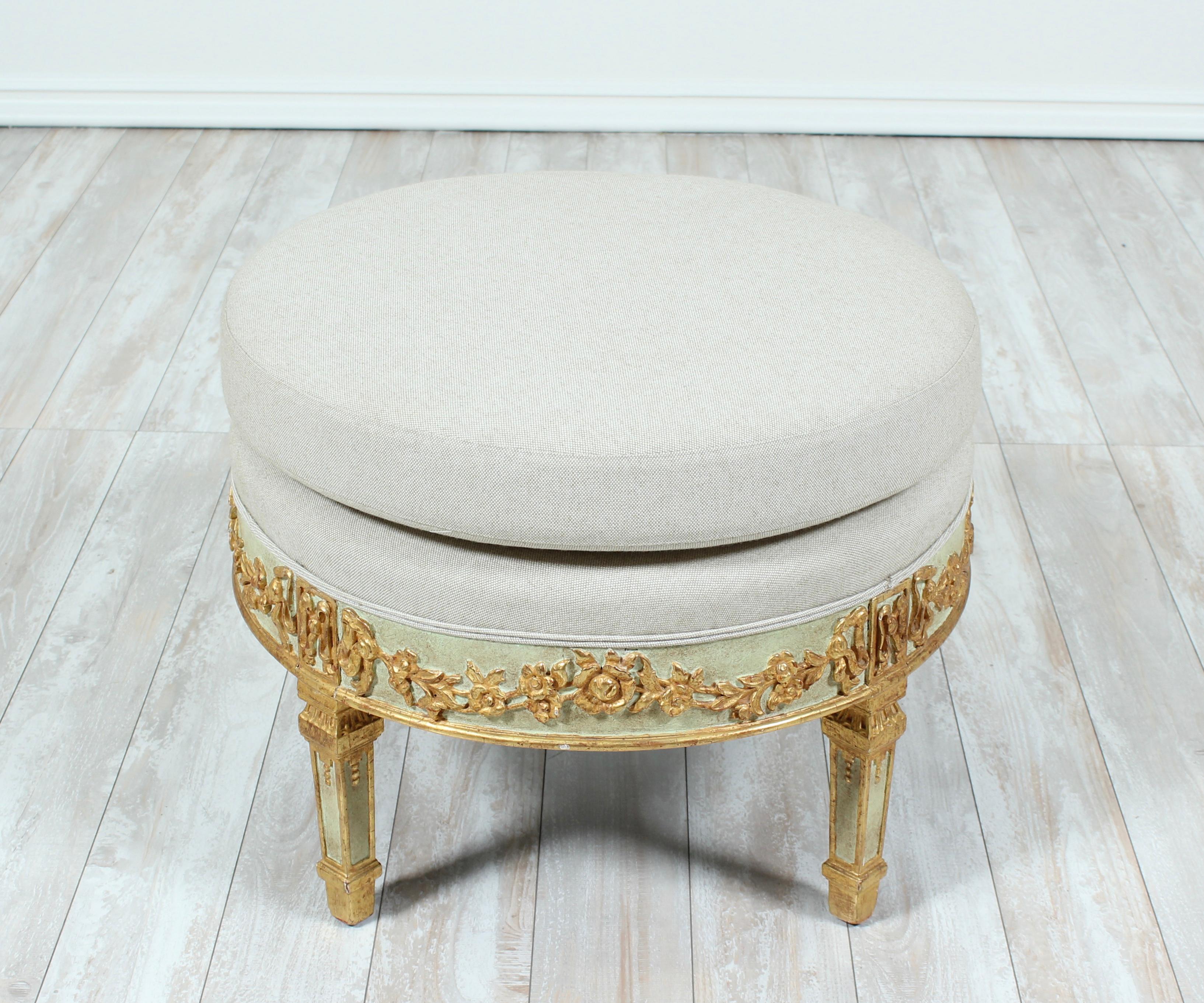 Beautiful Italian, 1940s aqua-green painted and parcel-gilt ottoman in the Neoclassical style. The ottoman feature a finely carve frieze consisting of flower garlands, bows and four tapered square legs. Newly upholstered in a fine linen textile.