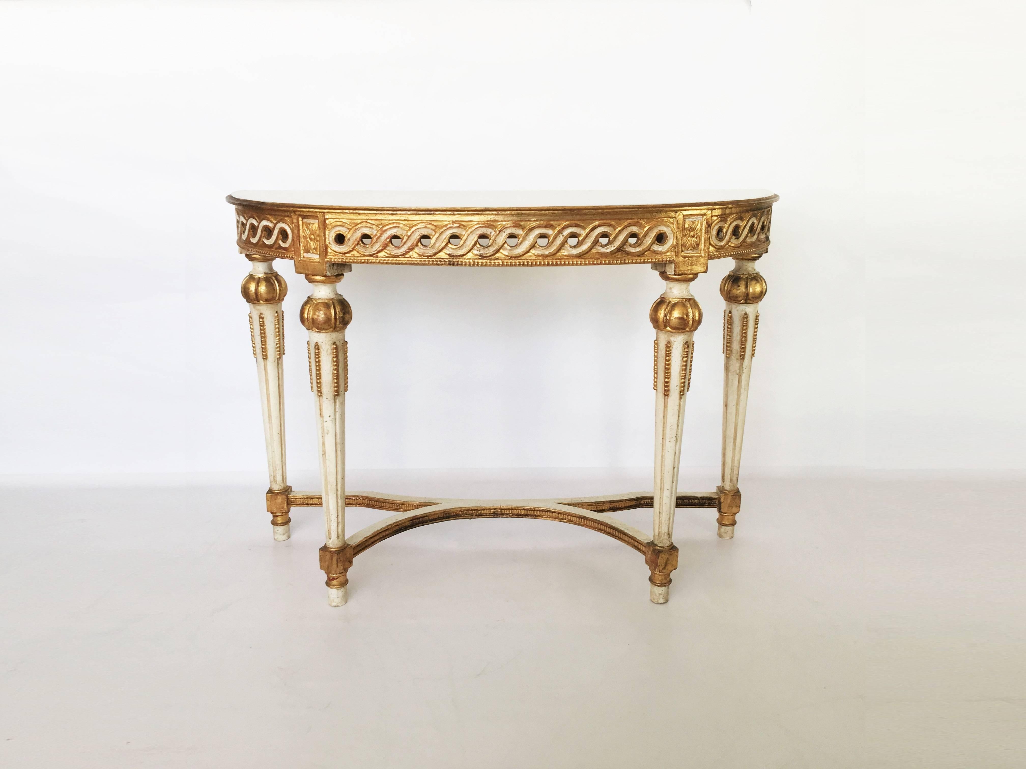 A fantastic example of neoclassic furniture! Early 20th century Italian hand carved, white painted and parcel-gilt console and mirror set. The console table featuring a conforming demilune top over a carved open work apron. Guilloche motif frieze
