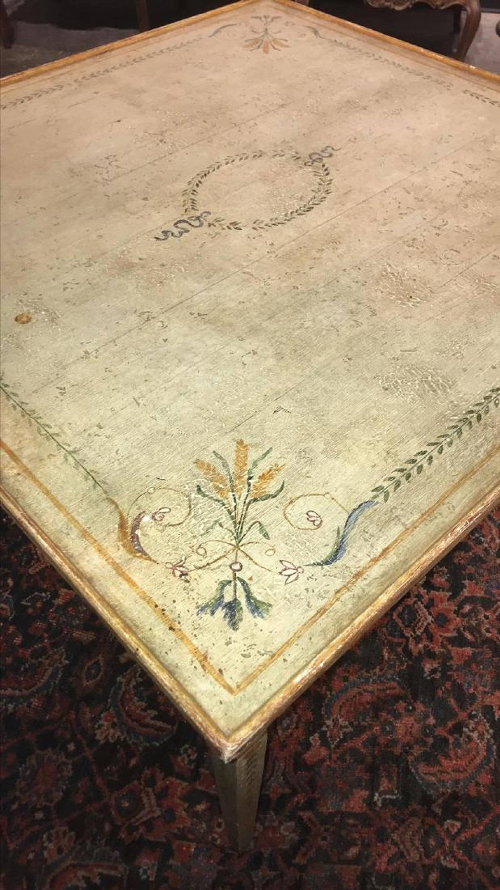 Lovely early 20th century Italian neoclassical style table, hand-painted in a floral and leaf design with gilt trim and having multiple drawers. The entire on square tapering legs.


