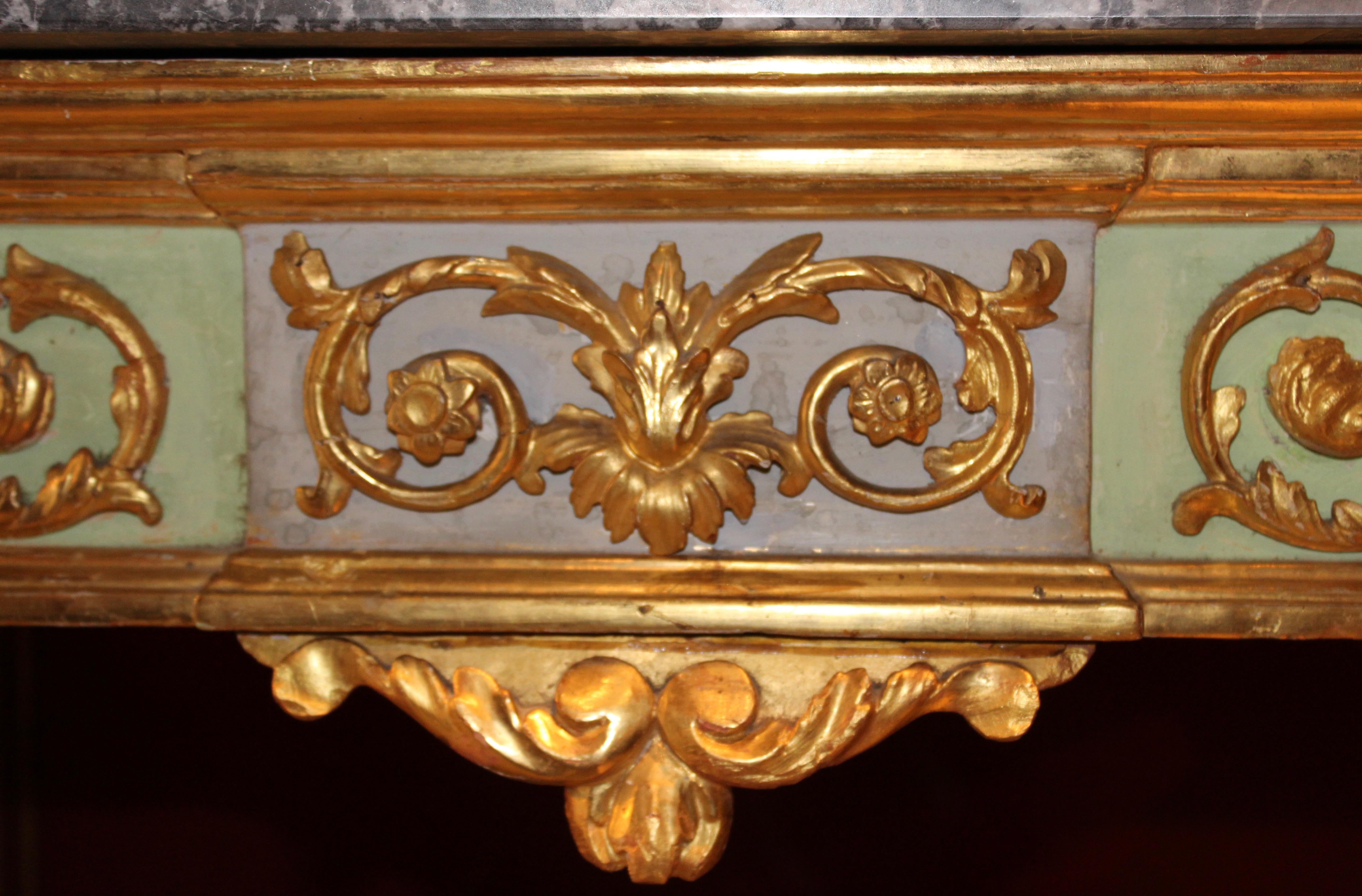 Italian neoclassical giltwood console with a later grey marble top, circa 1790. The grey marble top with white veining throughout, sits on top of a beautifully carved apron with carved gilt foliate scrolls on sections of green and grey painted wood,