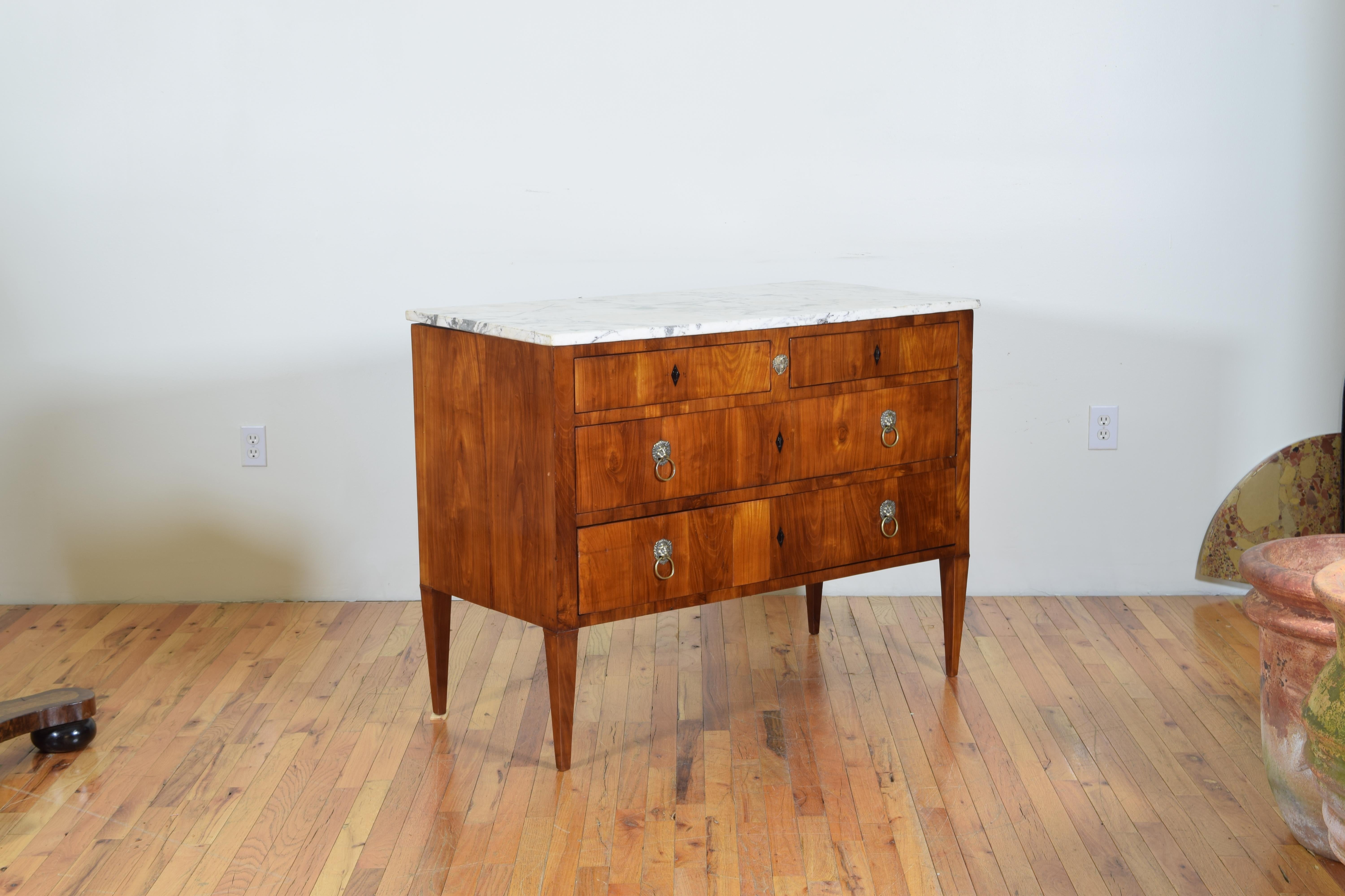 most likely Tuscan, having a rectangular white and black veined marble top resting on a conforming case housing two upper drawers above two larger drawers, raised on tapered legs, with ebonized escutcheons and lion mask brass pulls