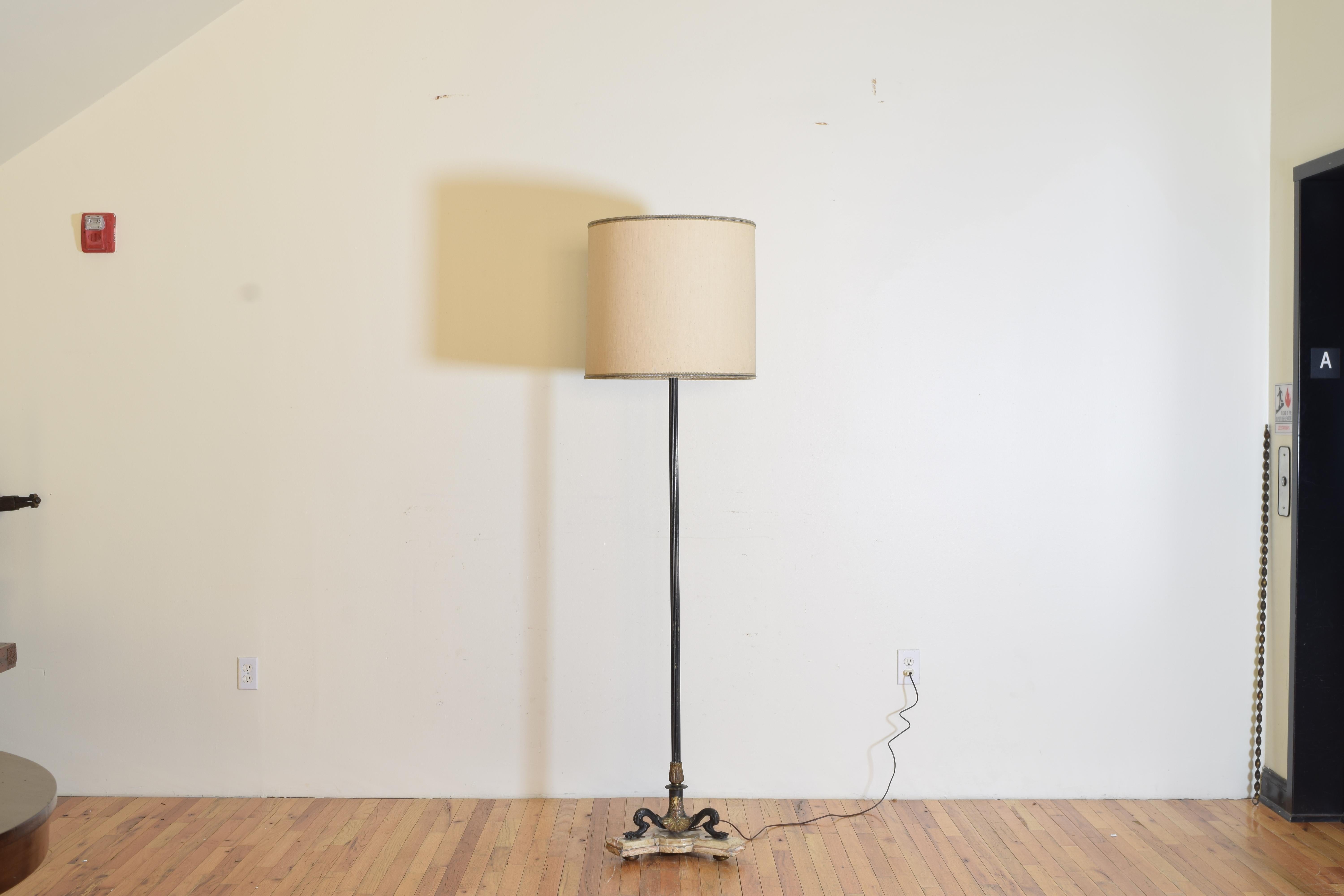having a slender black-painted reeded column the top detailed cast brass bobeche and candle cup, the tripartite base is comprised of 3 paw feet surmounted with gilt brass shell-forms, all resting atop a conforming tripartite onyx base resting on