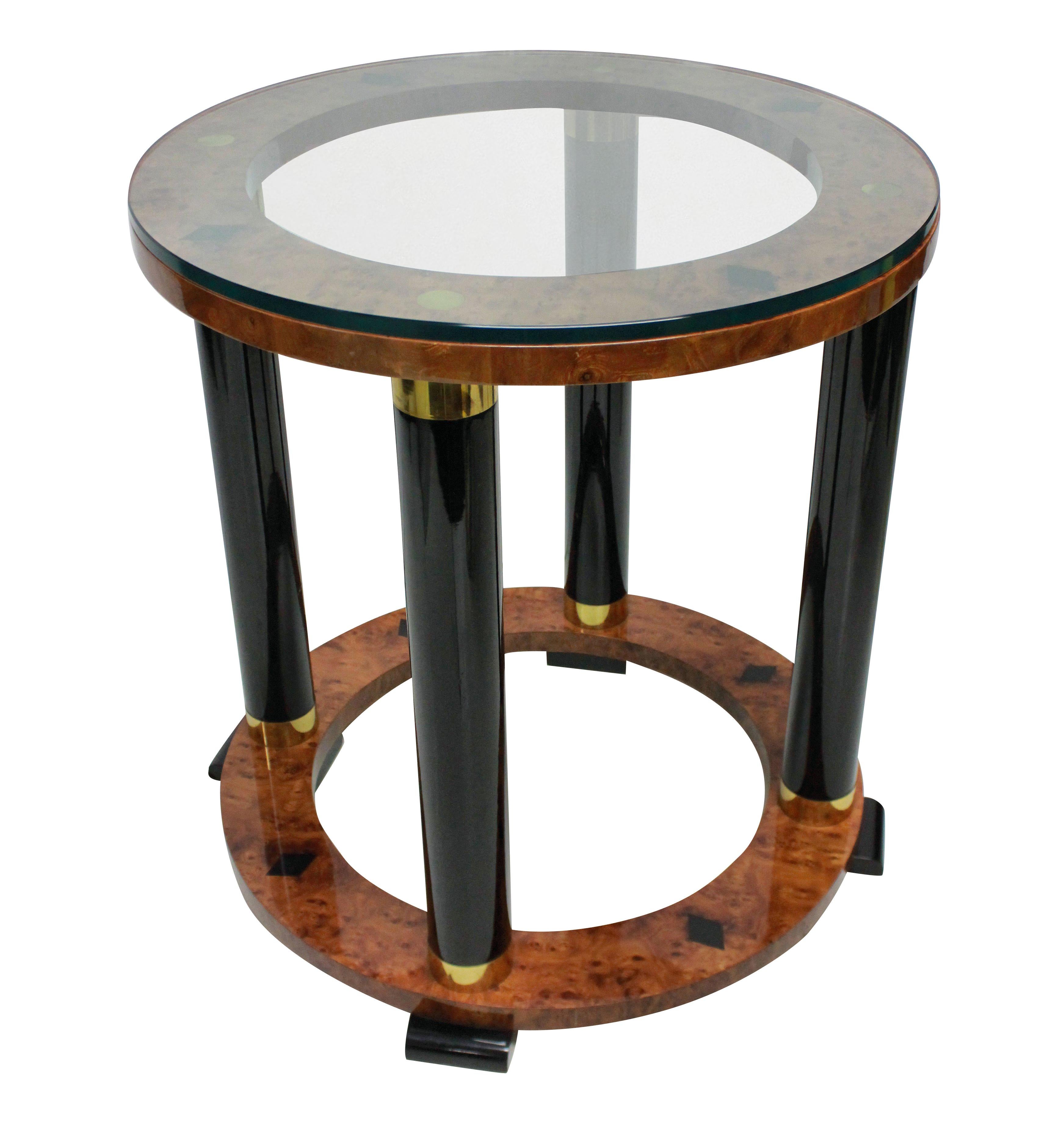 An Italian neoclassical circular side table in lacquered walnut and ebony with brass inlay and a glass top.