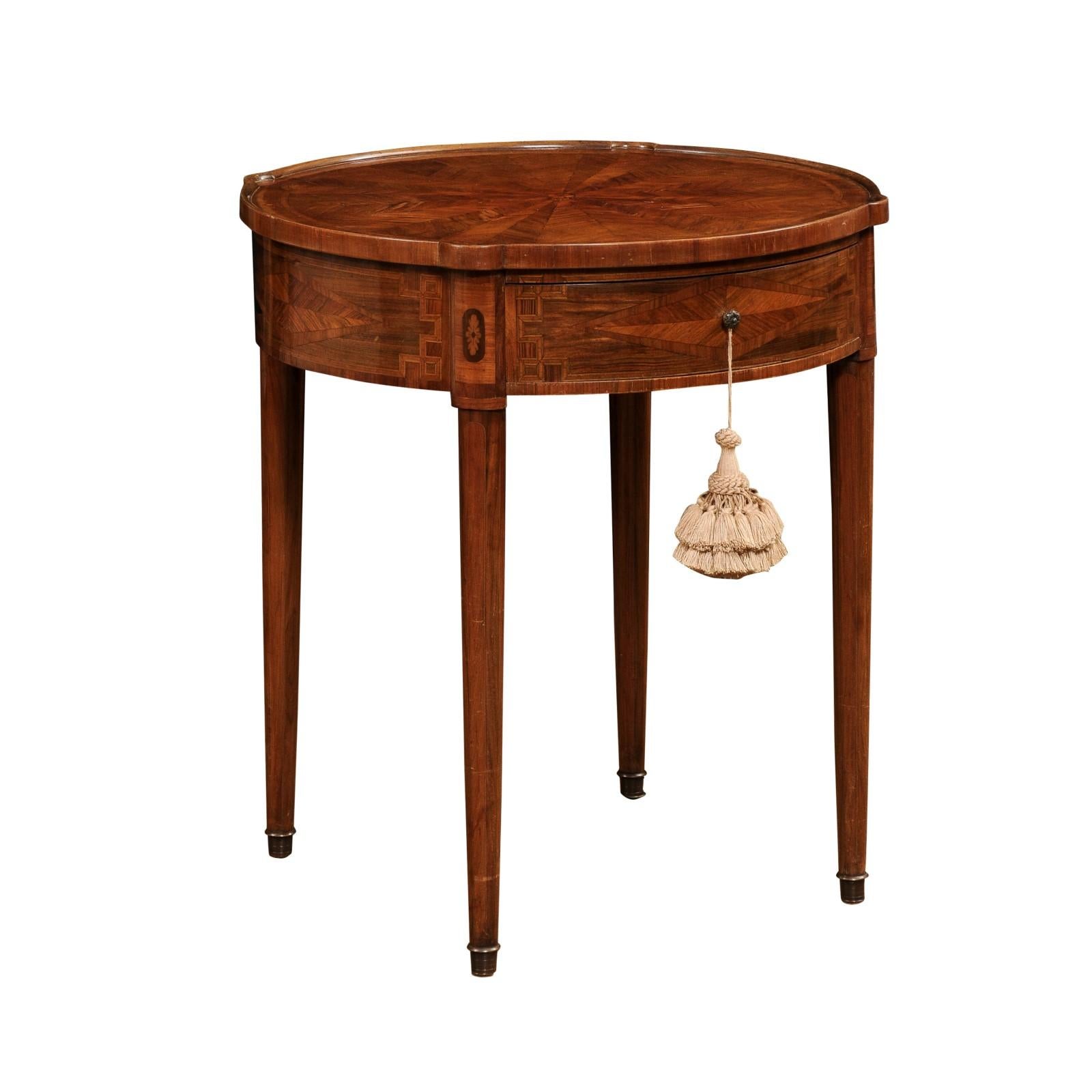 An Italian Neoclassical style mahogany and walnut center table from the 19th century with marquetry décor, round top, single drawer and cylindrical tapering legs. Created in Italy during the 19th century, this center table captures our attention