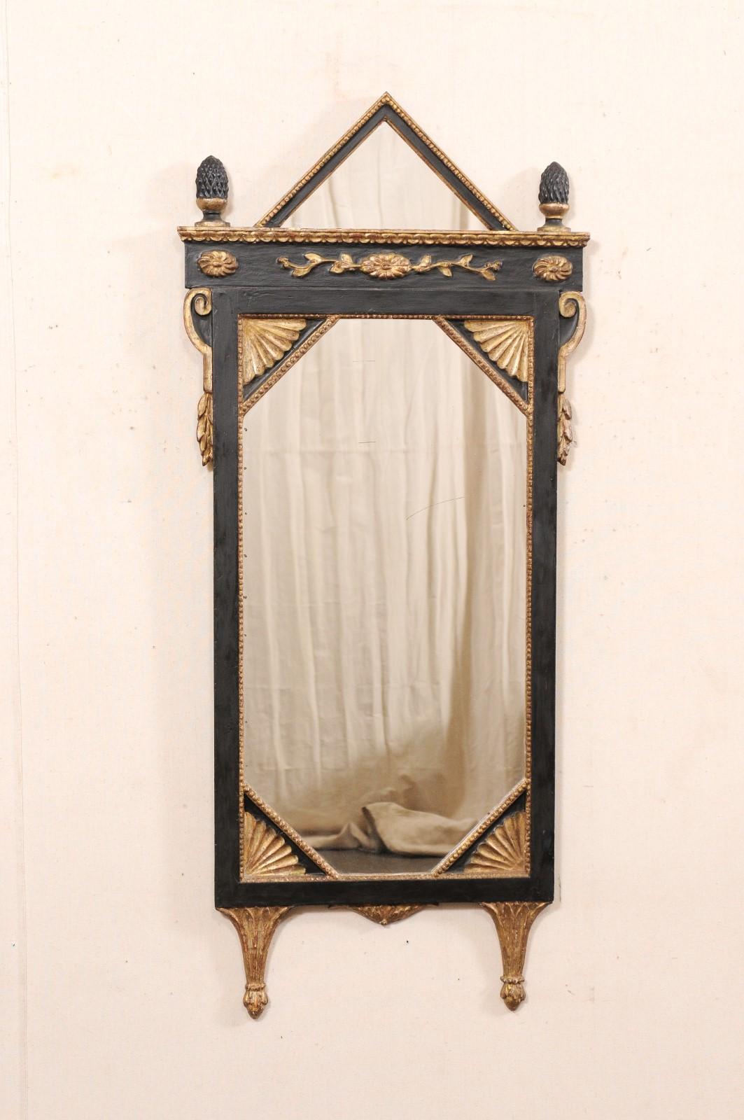 Specchio in legno intagliato e dipinto in stile neoclassico italiano dei primi del Novecento. Questo specchio antico proveniente dall'Italia è caratterizzato da un'esclusiva cresta triangolare in rilievo con piccole perline, un paio di terminali a