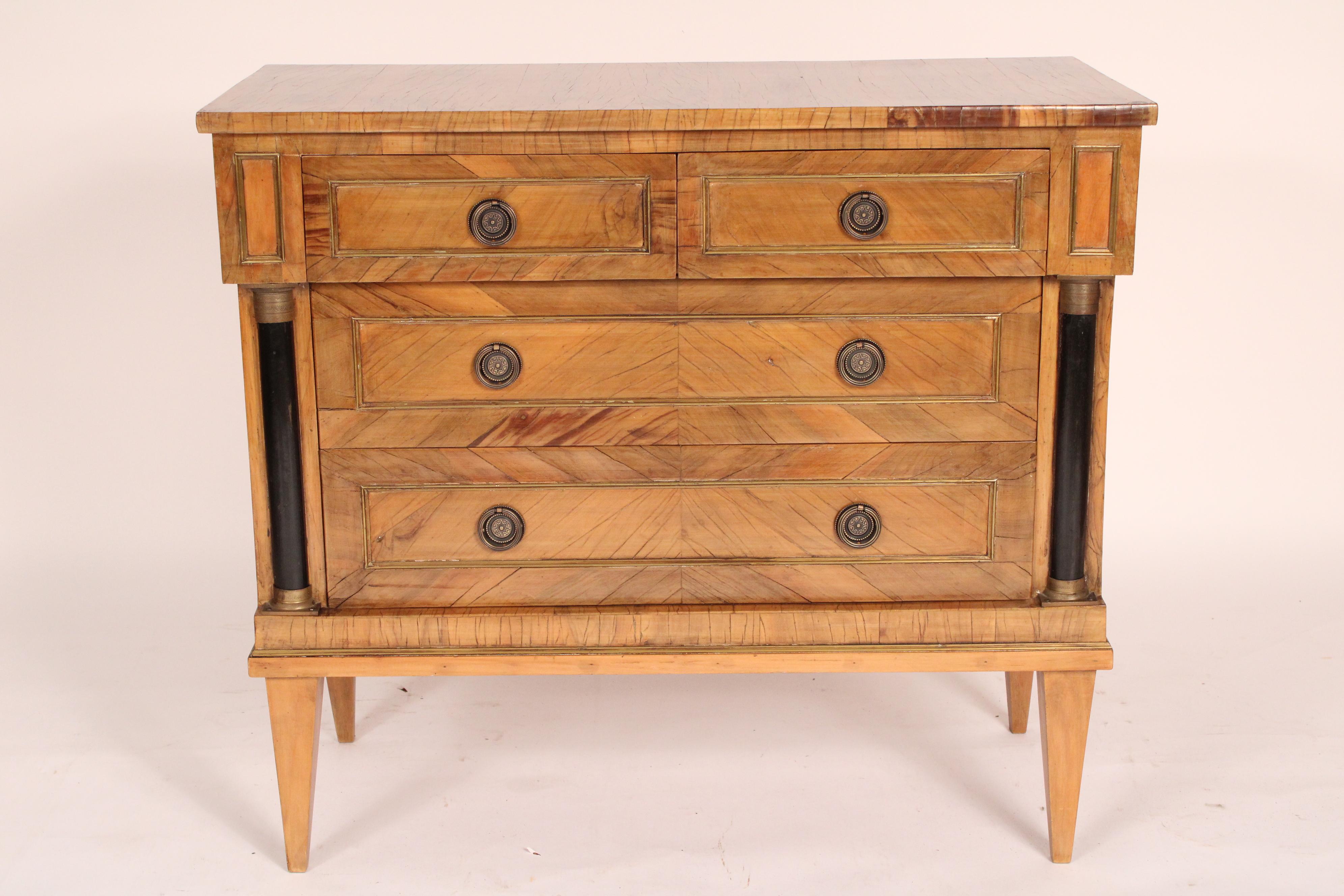 Italian neo classical style walnut and fruitwood chest of drawers, circa 1960. With a rectangular top, two top drawers and two lower drawers all with inset brass trim and brass drawer pulls, flanked by black lacquer columns with brass capitals and