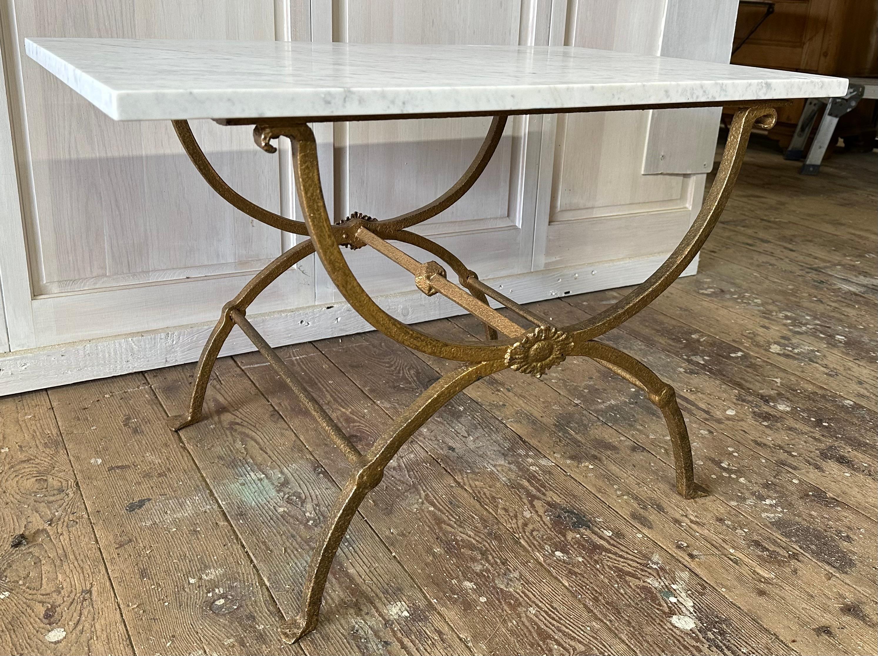 Add style and presence to any room with this beautifully aged patinated Italian coffee table featuring a rectangular white carrara marble top supported by sculptural base having curule legs crafted from iron. The table is stable and solid with
