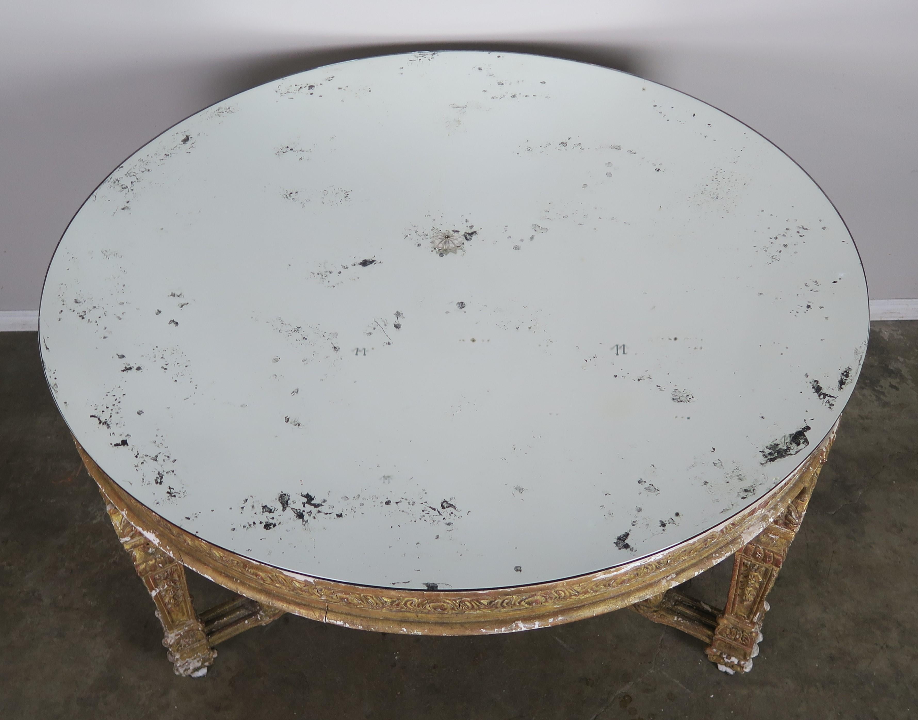 Italian neoclassical style giltwood center table standing on three straight legs that join together with a bottom stretcher. Antique mirrored top with center rosette.