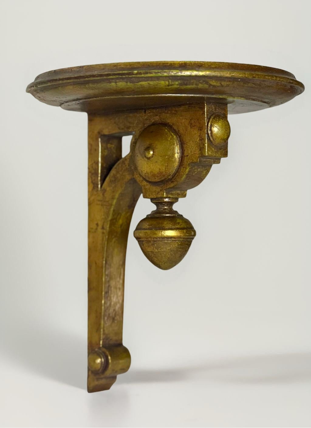 Pair of Italian Neoclassical style giltwood wall bracket shelves, circa early 1900s. A unique design having boldly carved and outstanding details with a desirable, nicely aged patina. A near-circular platform with a finely shaped edge provides great