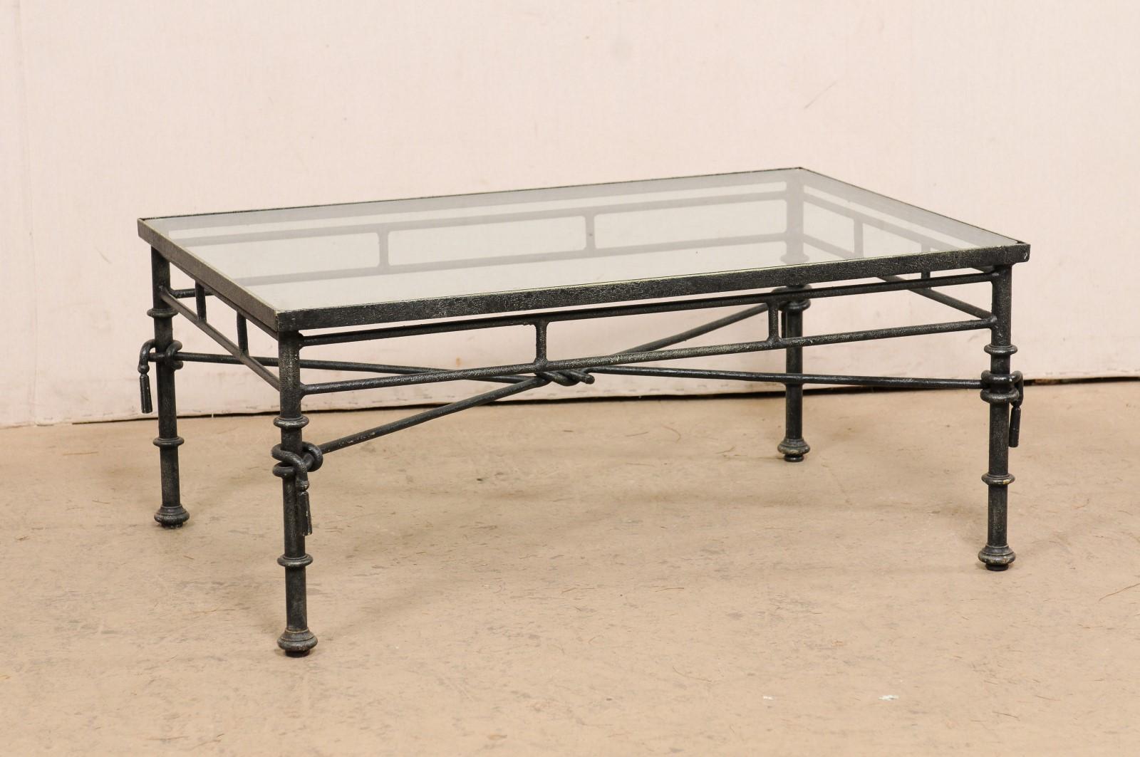 An Italian Neoclassical style table with glass top. This vintage table from Italy, with it's Neoclassical influences, has a rectangular-shaped glass top, which rests within an iron frame and base. The iron base of this table is open and airy, there