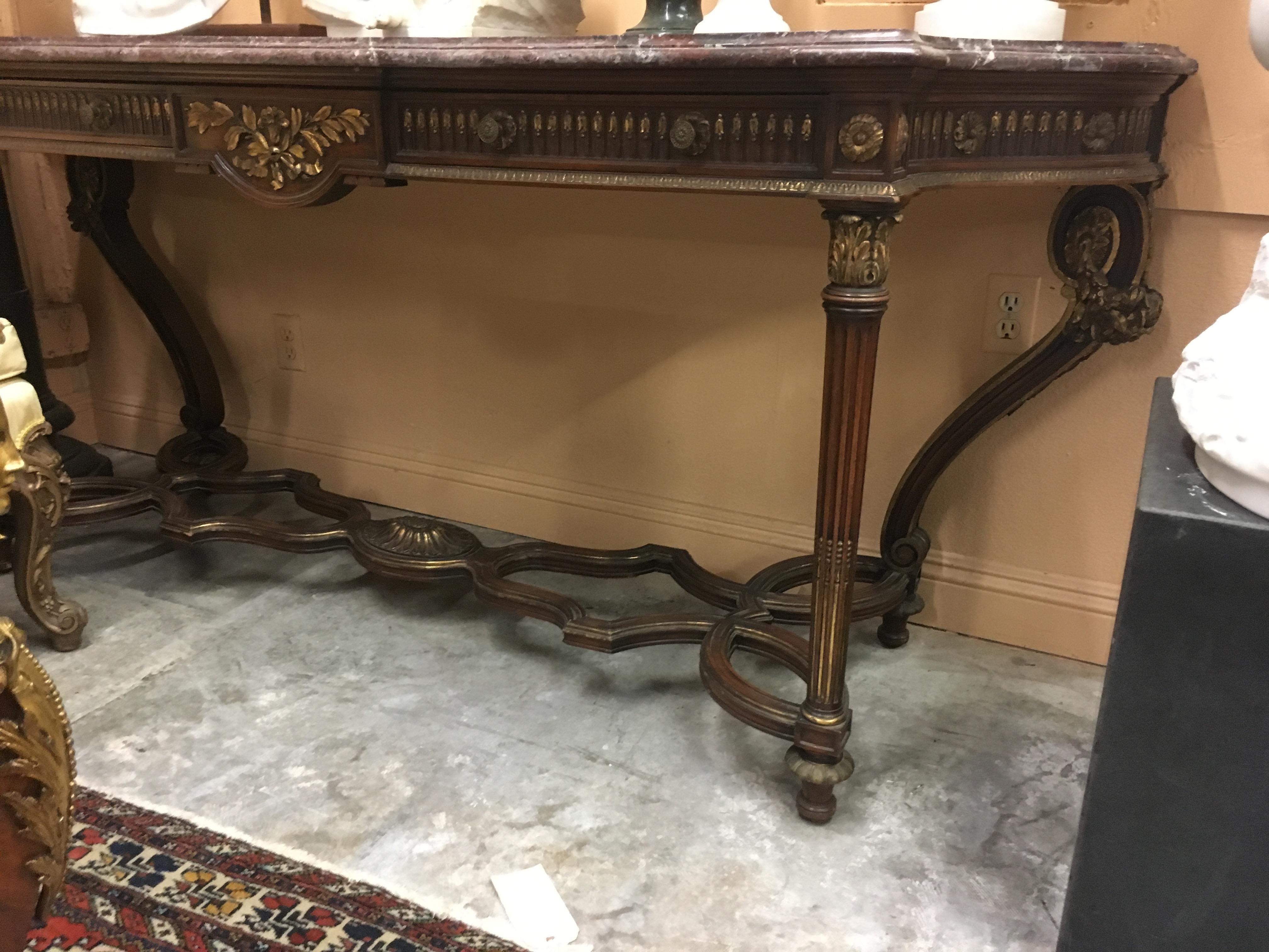 Spectacular Italian neoclassical style parcel-gilt beachwood and marble console table, late 19th-early 20th century.

The moulded purple and Rouge marble top is over a neoclassical style frieze fitted with two drawers beautifully carved with
