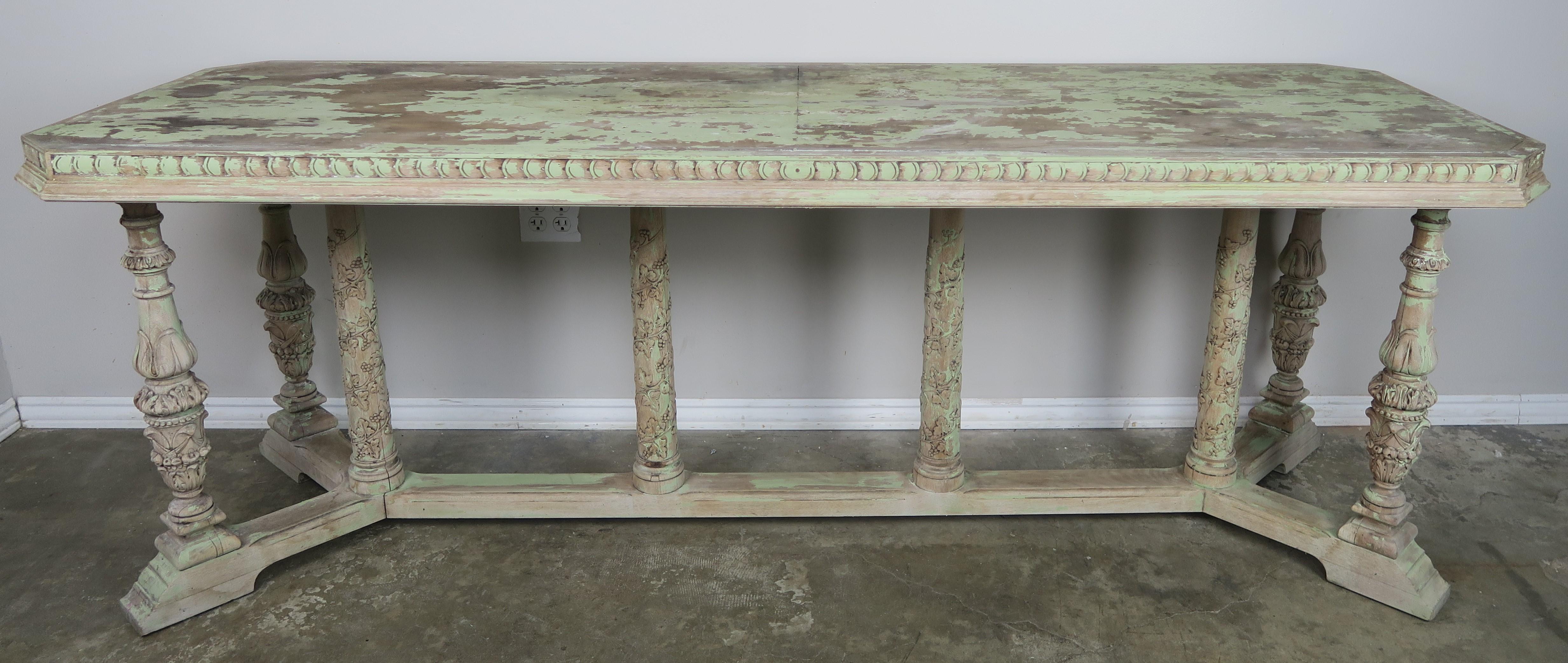 Italian painted Neoclassical style carved console standing on four legs that are connected by a center stretcher with four columns adorned with flower decoration.  The console is painted in a celadon green coloration that is beautifully worn and