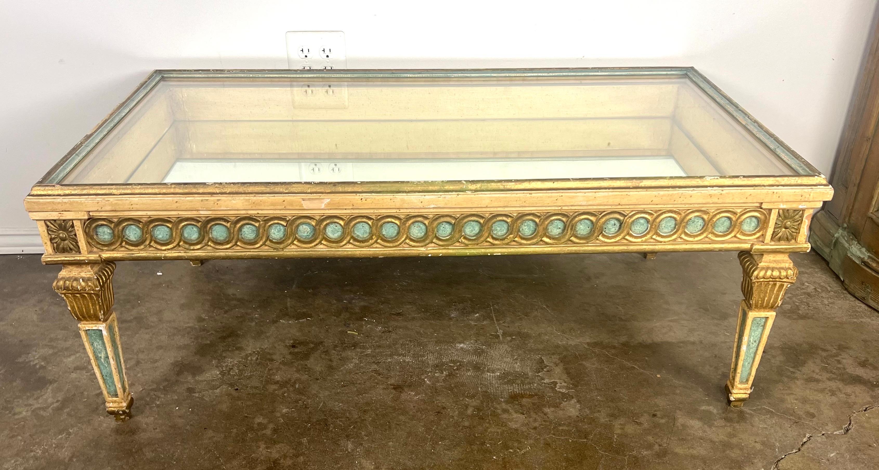 Italian Neoclassical style coffee table with fluted, column-like legs and a distinctive array of medallion motifs encircled by stylized frames on the side panels.  The blue-green color on the legs and frames adds a touch of vintage charm,
