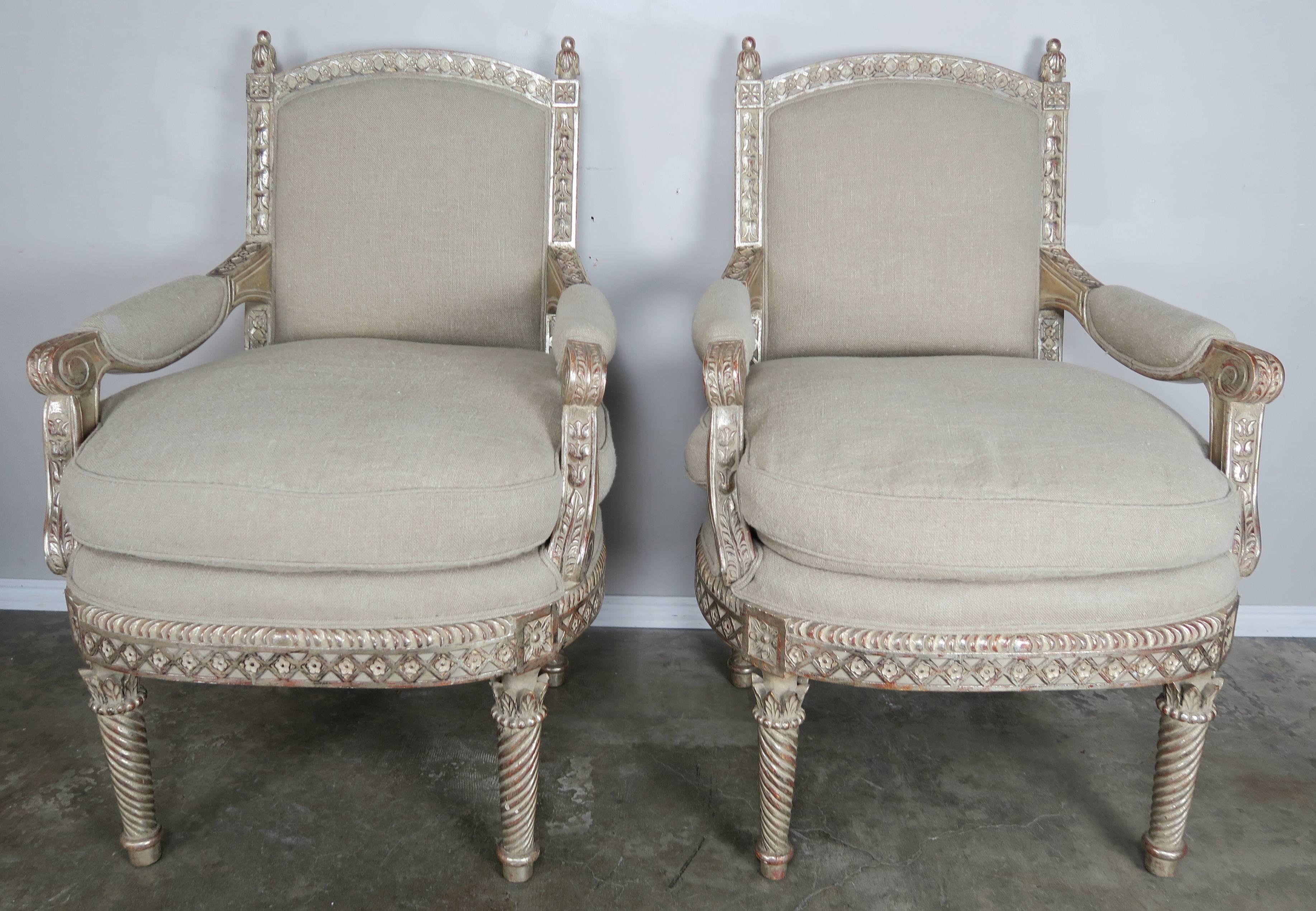 Italian neoclassical style silvered gilt armchairs newly upholstered in a washed Belgium linen with down filled loose seat cushions. The intricately carved neoclassical style armchairs stand on four straight legs. Great armchairs for both