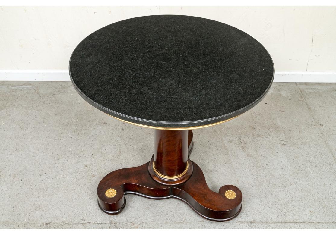 Une table très décorative et bien faite de William Switzer. Fabriquée à la main en Italie, la table a un air résolument néoclassique avec la touche moderne d'une base tourbillonnante en acajou choisi avec des accents dorés. Le plateau est un granit