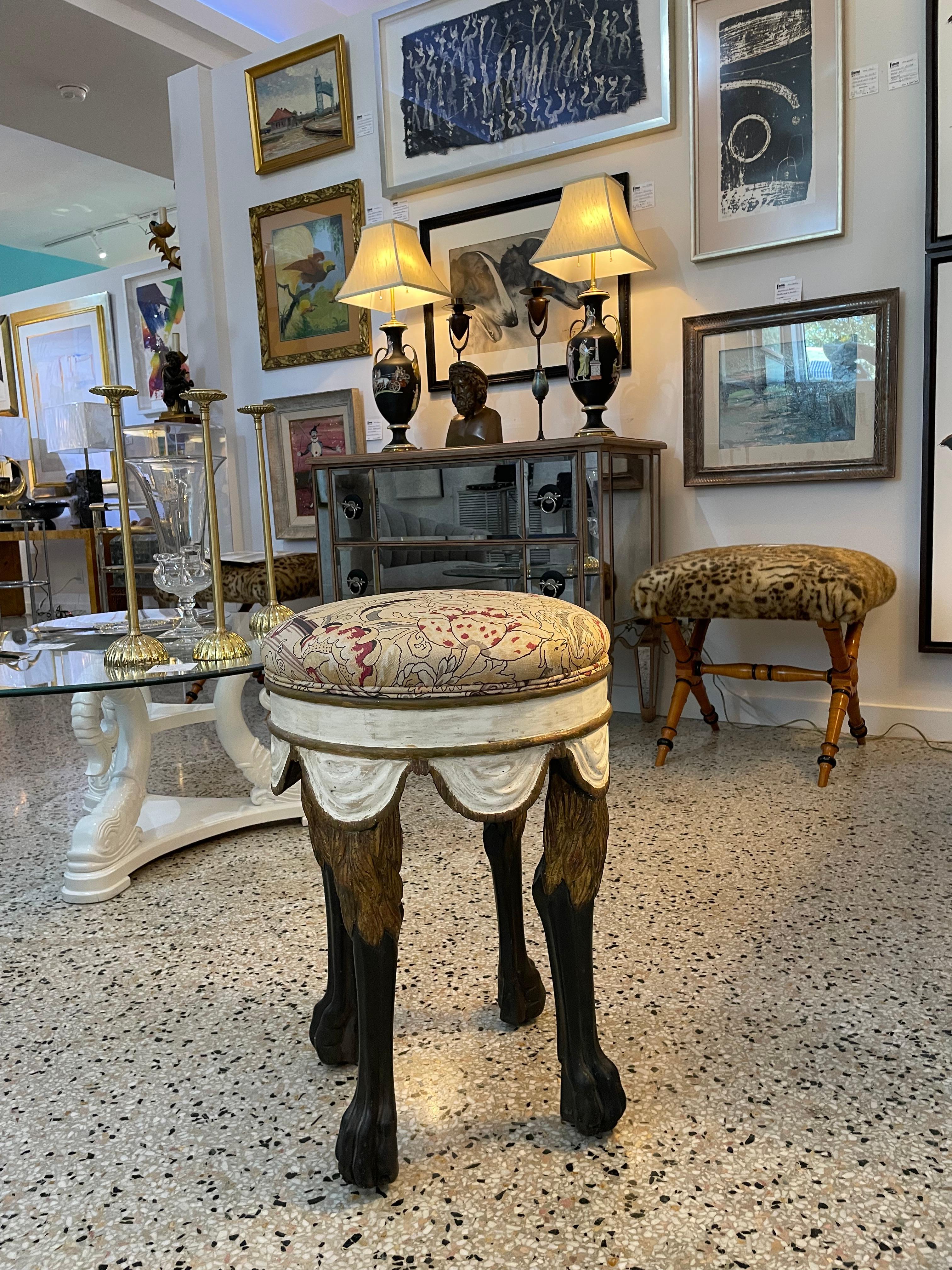 This stylish and chic Italian stool dates to the 1990s and is hand carved and hand painted, with swagged fabric and stylized lions leg and paws.  The woven fabric is a Renaissance motif of birds and flora.

it is possible that this was once used as