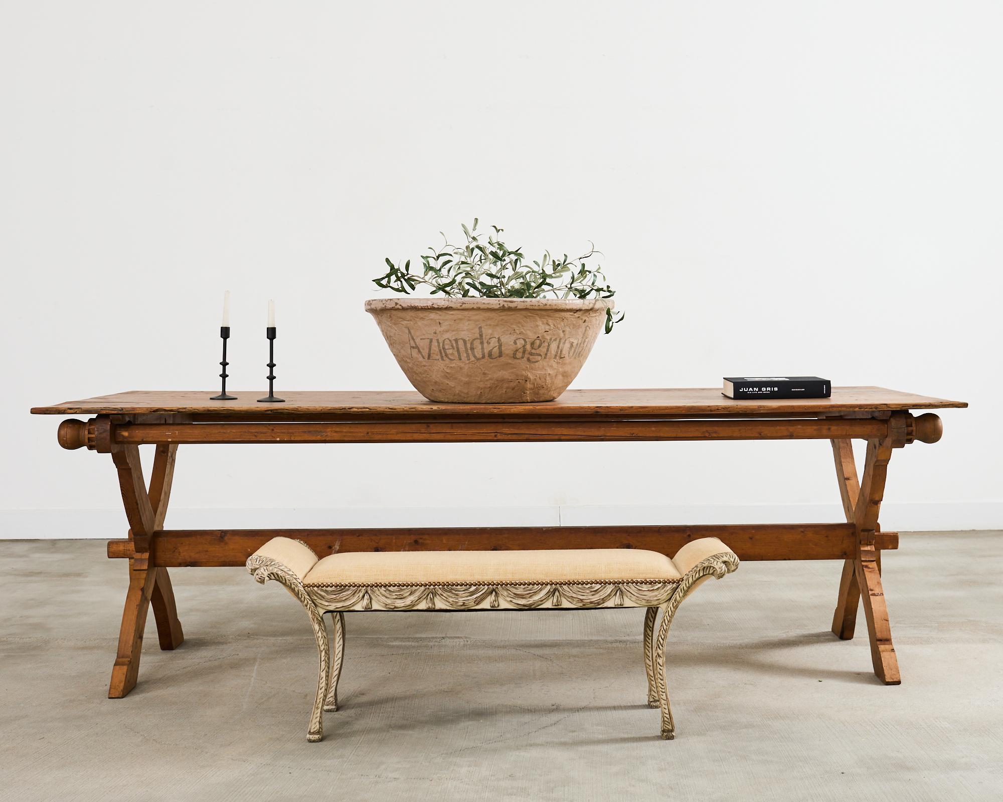 Gorgeous Italian window bench crafted in the neoclassical taste featuring carved plume feathers and swag. The trompe l'oeil bench is hand-carved from beech with an intentionally distressed painted finish. The seat is upholstered with soft jute