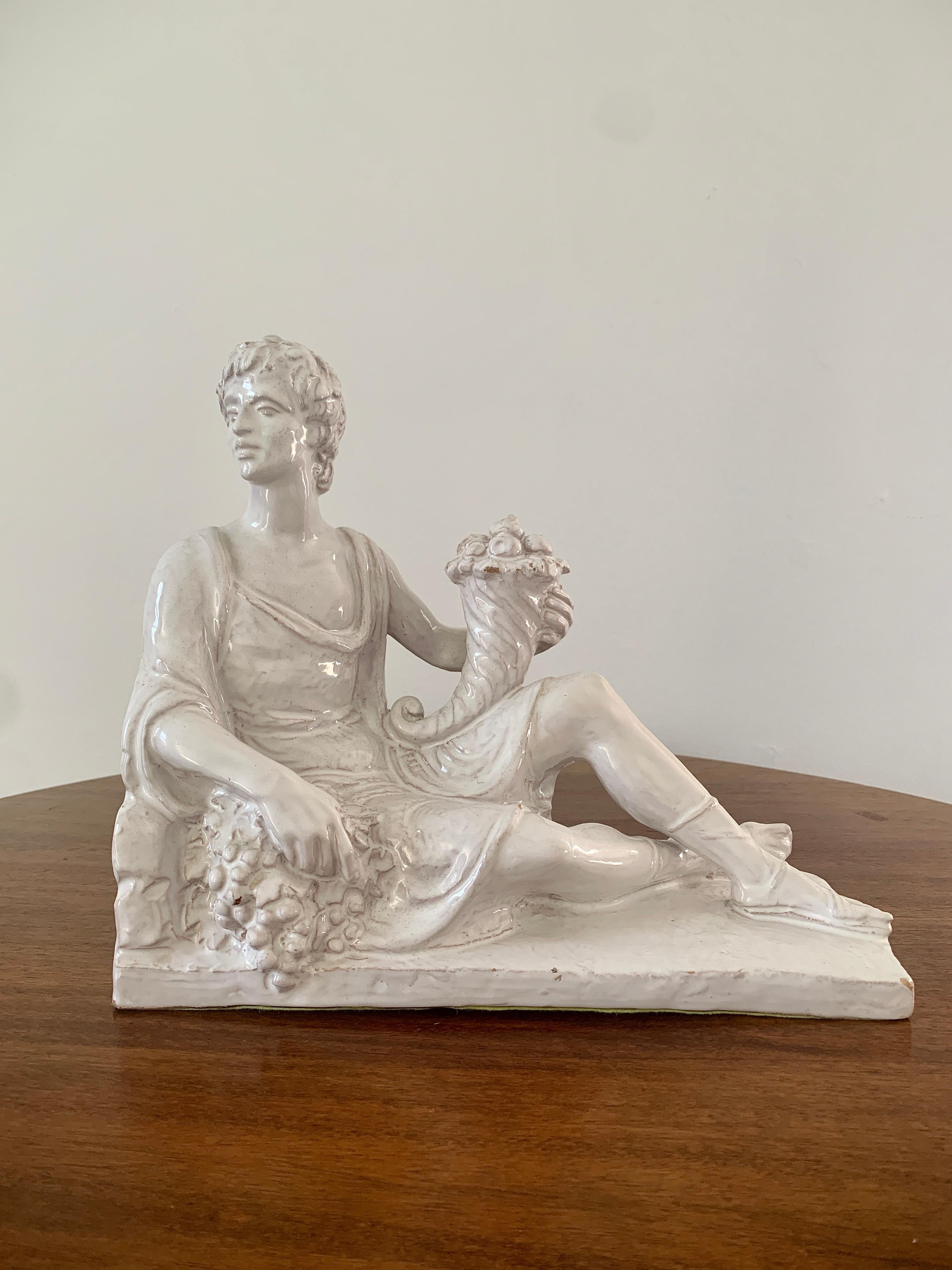 A gorgeous neoclassical style white porcelain sculpture of a reclining man holding a cornucopia

Italy, Circa 1960s

Measures: 11.25