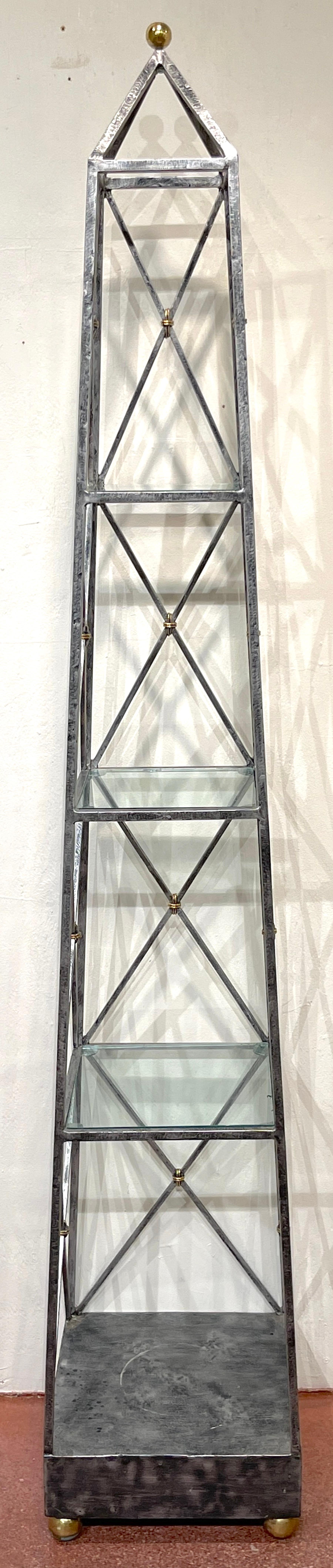Italian Neoclassical Wrought Iron & Brass Obelisk Etagere 
Italy, circa 1980s

A sleek design, the open work obelisk with a brass orb finial. Beautifully made of polished wrought iron joined with brass 'X' rope ties, fitted with three tapering