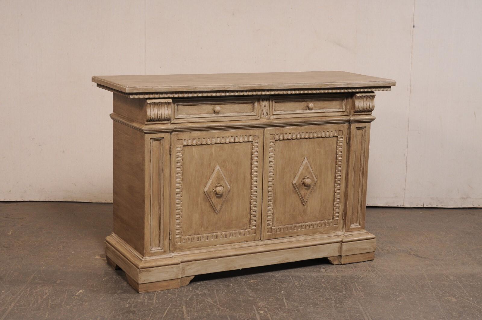 Una credenza italiana in legno, con dettagli ben rifiniti, del XX secolo. Questo mobile buffet d'epoca proveniente dall'Italia ha un piano di forma rettangolare con la parte inferiore delineata da una cornice a lingua d'agnello. La parte superiore