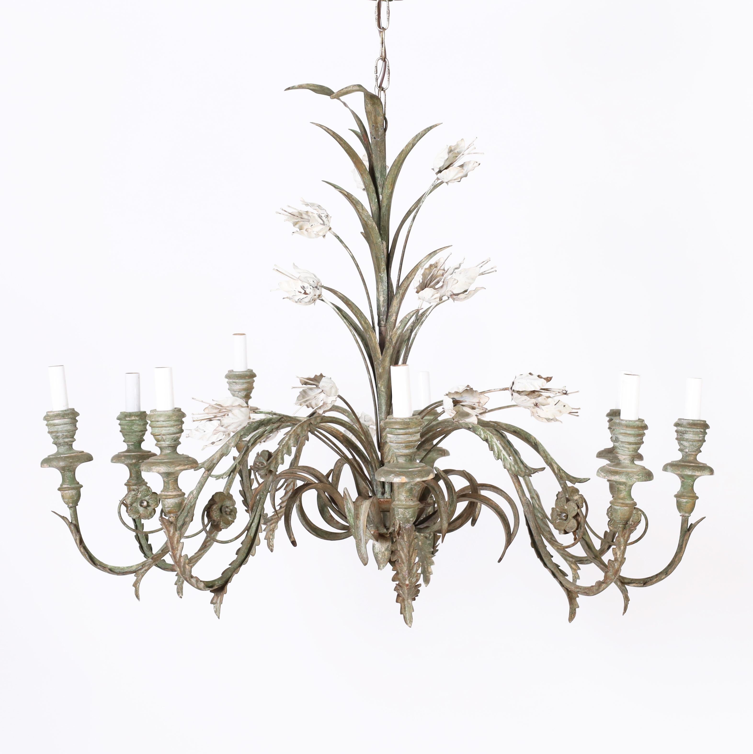 Classic Italian chandelier crafted in metal with a sheaf shaft, nine arms with acanthus leaves and flowers and turned wood candle cups, all with a worn oxidized painted finish and featuring white enamel tulips.