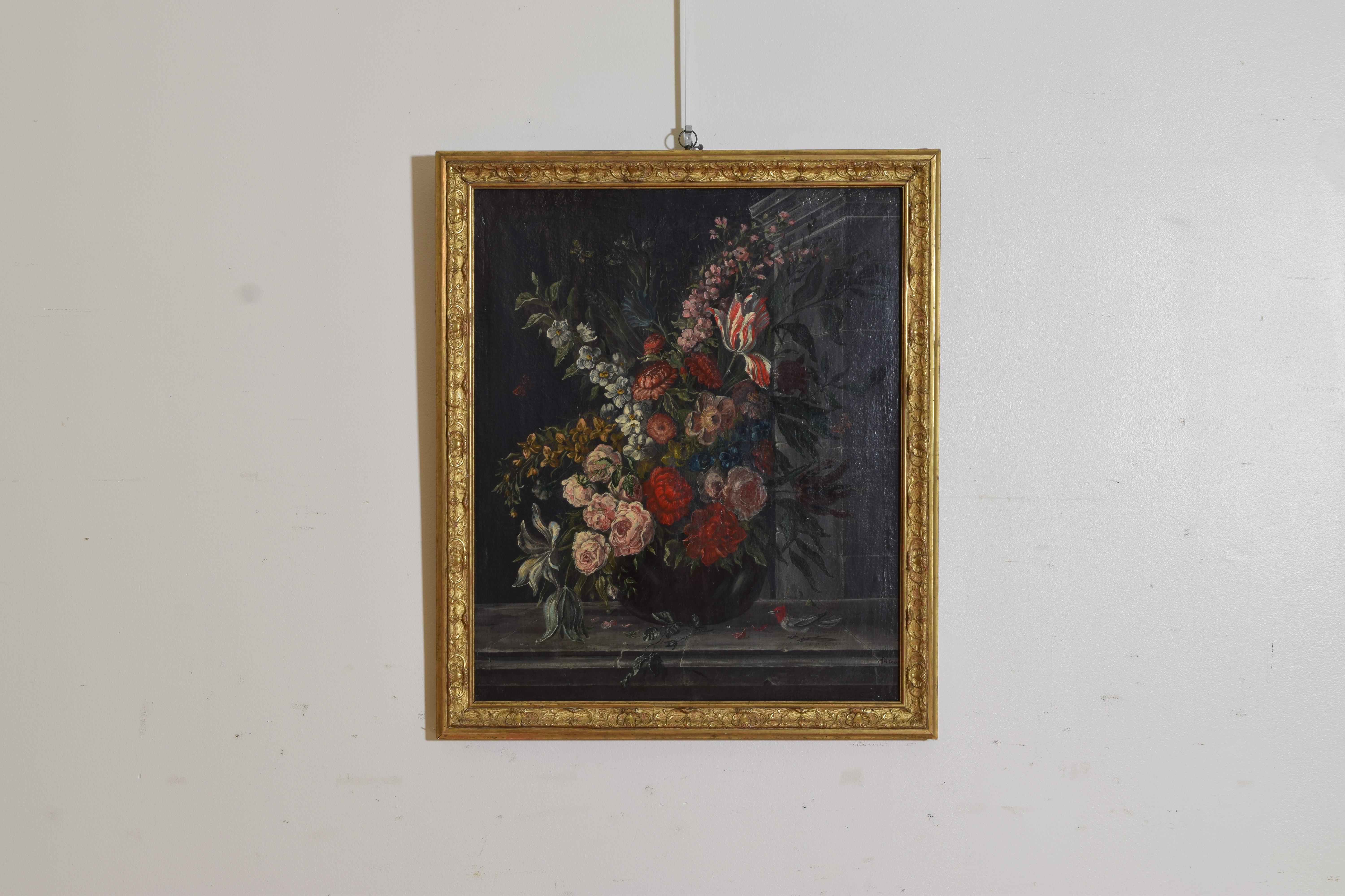 Depicting a vibrant bouquet of flowers in a vase placed on a stone window sill with flying butterflies and a red bird, retaining a period carved giltwoood and gilt gesso frame, signed lower right 
