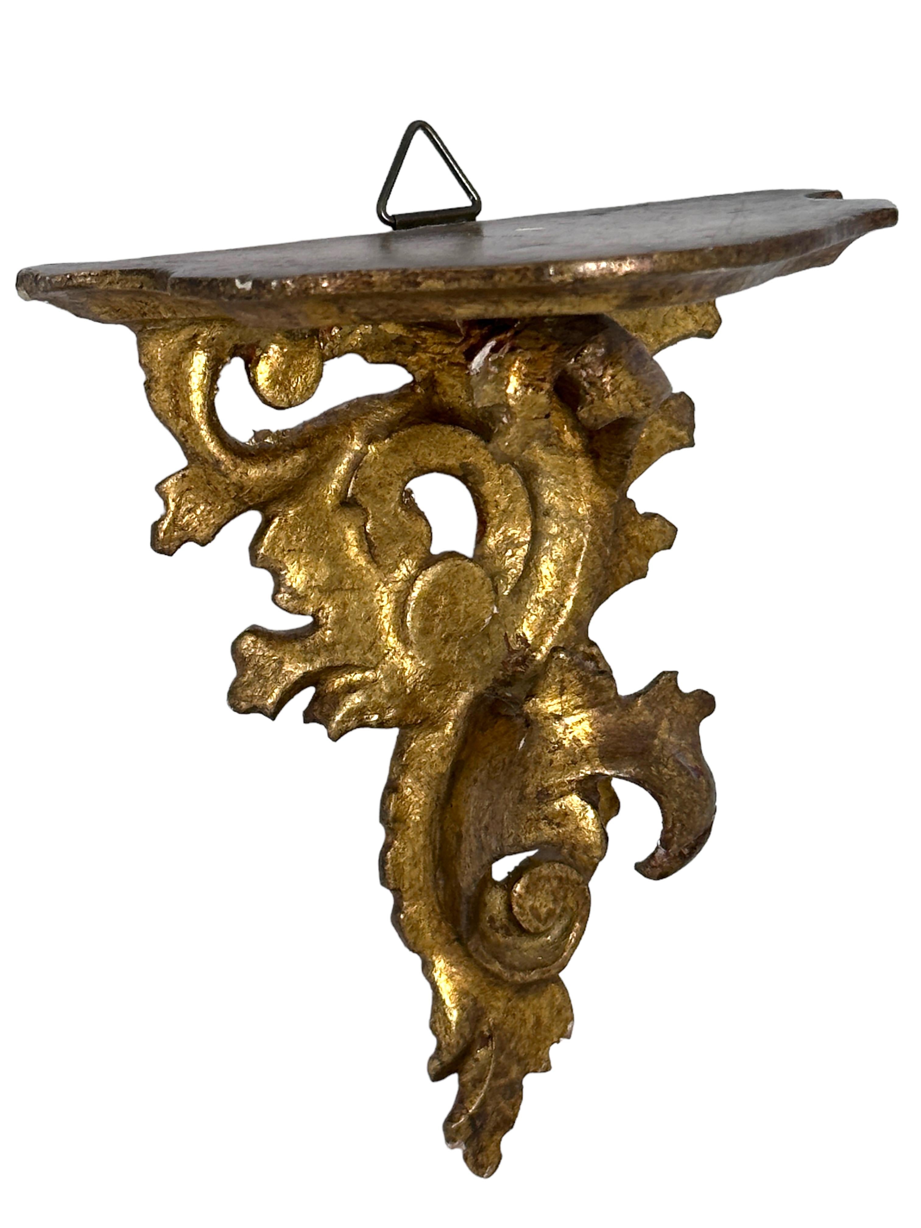 Offered is an absolutely stunning, 1950s Italian gilt wood miniature wall shelf or wall console. Minor patina and paint lost gives this piece a classy statement. Made of hand carved wood and gold plated. A nice shelf to present a statuette or a