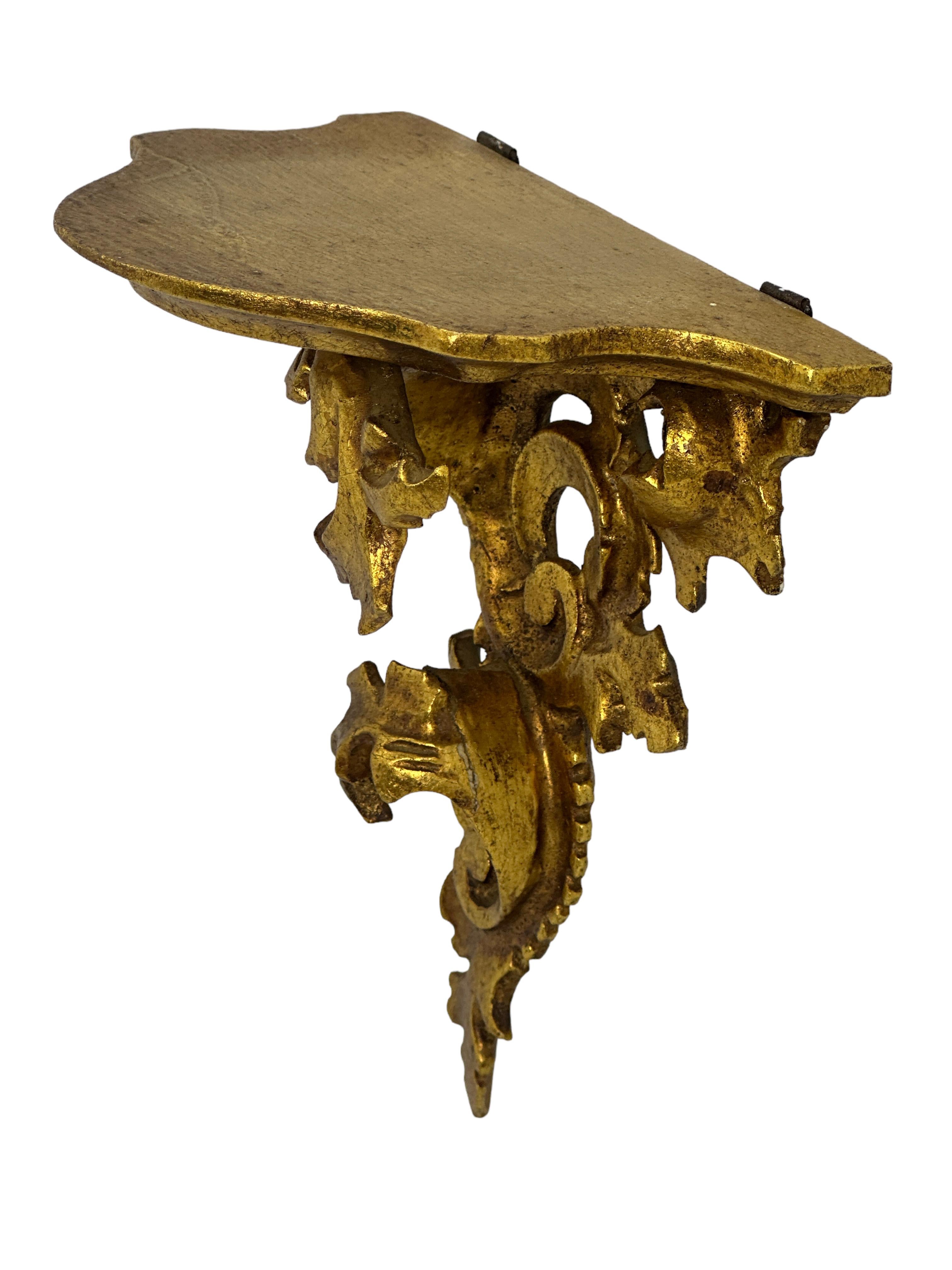 Offered is an absolutely stunning, 1950s Italian gilt wood wall shelf or wall console. Minor patina gives this piece a classy statement. Made of hand carved wood and gold plated. A nice shelf to present a statuette or a beautiful object. A nice