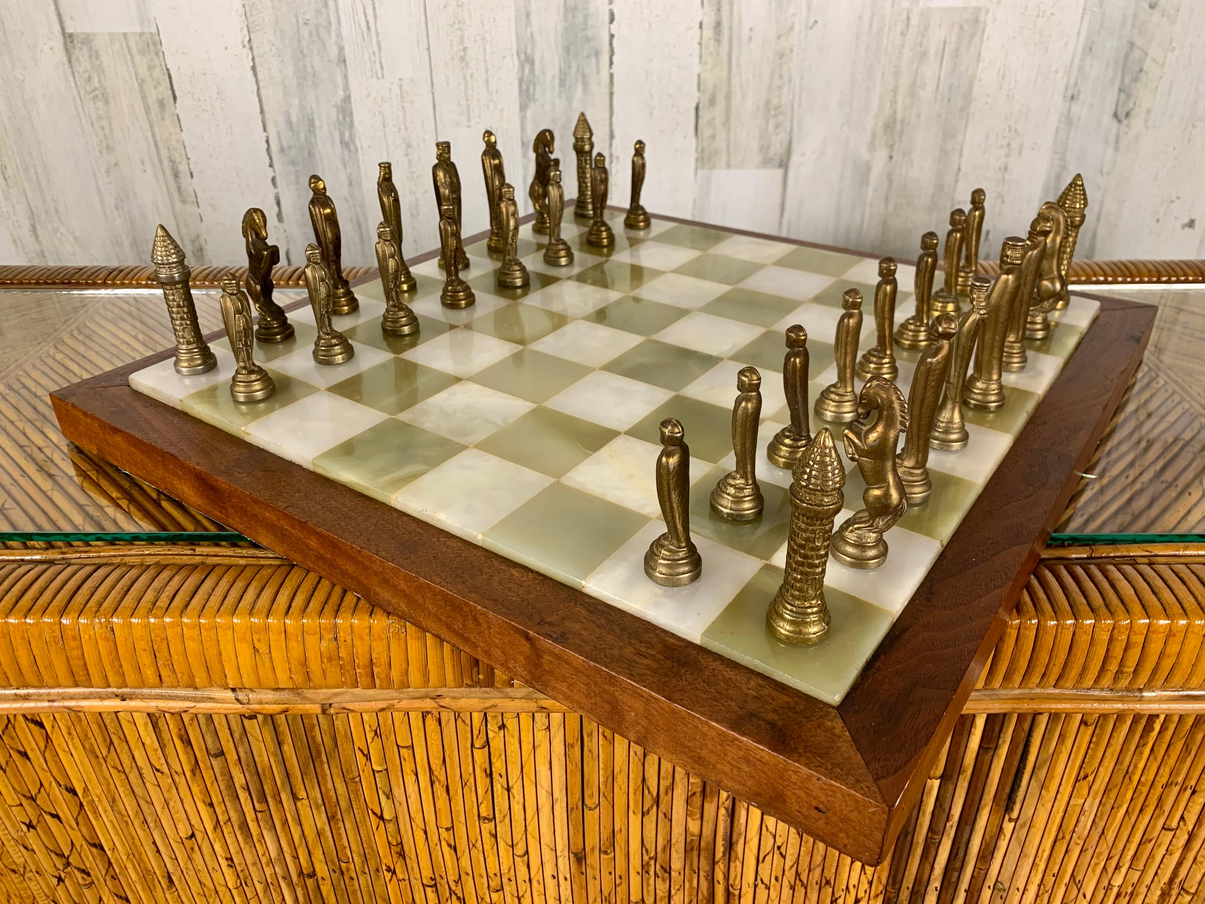 Combination of white and green onyx on a walnut frame with brass chessman. The wood box is covered in gold embossed leather with upholstered interior. This set includes game board, brass chessman and leather covered box.